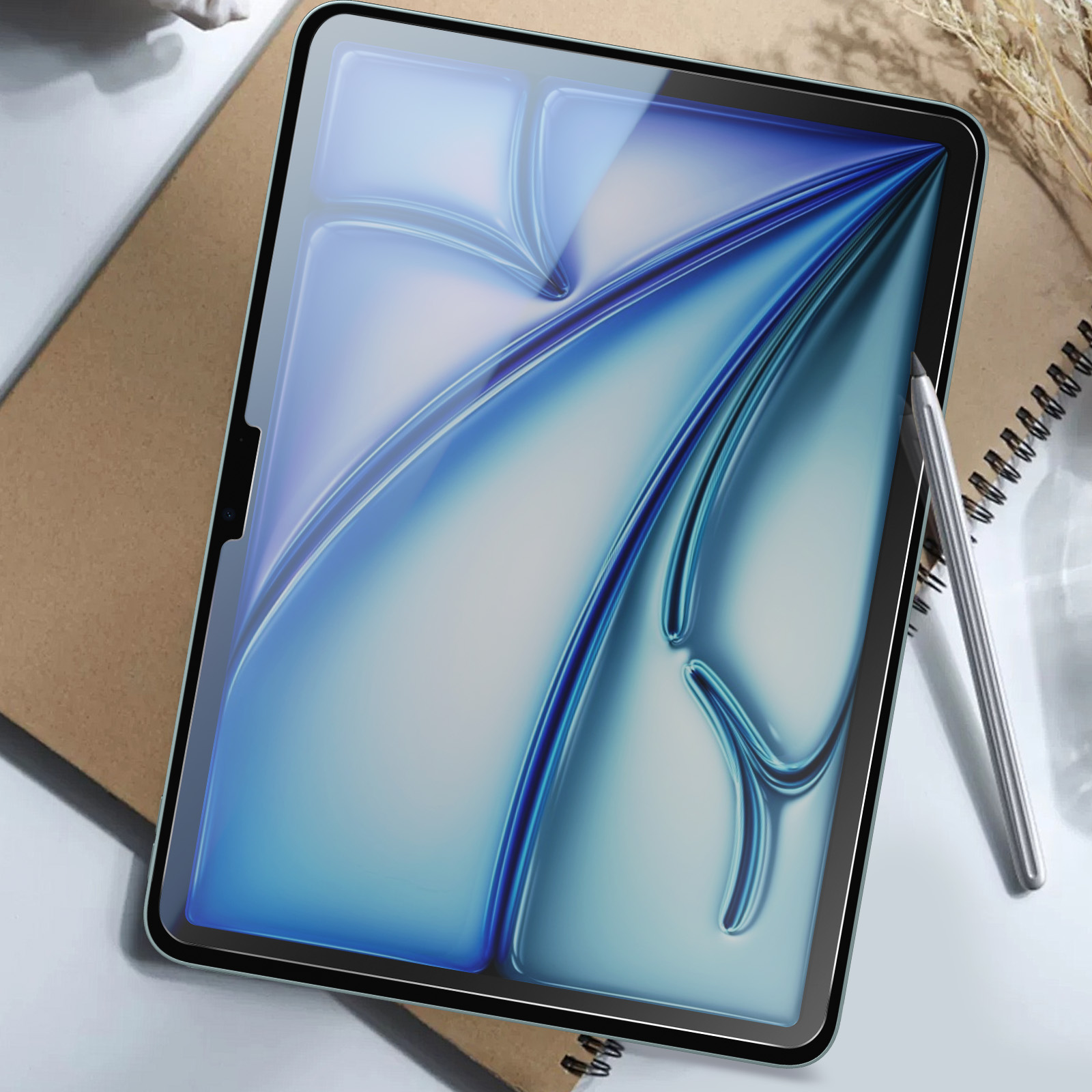 Tablette avec protecteur d'écran, stylo et un carnet sur un bureau.