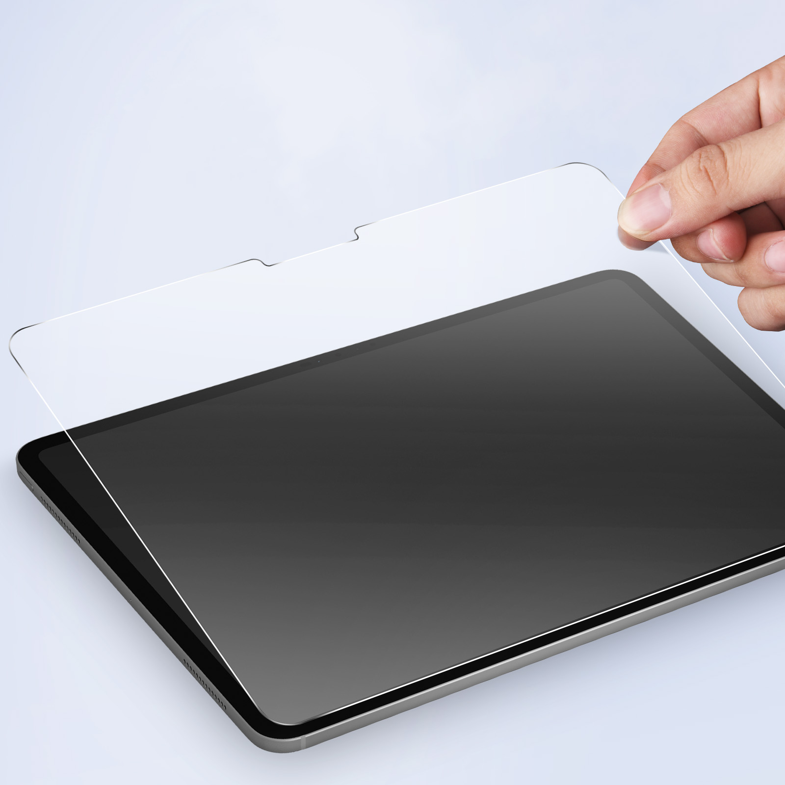 Una mano che tiene una protezione per lo schermo trasparente sopra un tablet. Il tablet ha uno schermo nero.