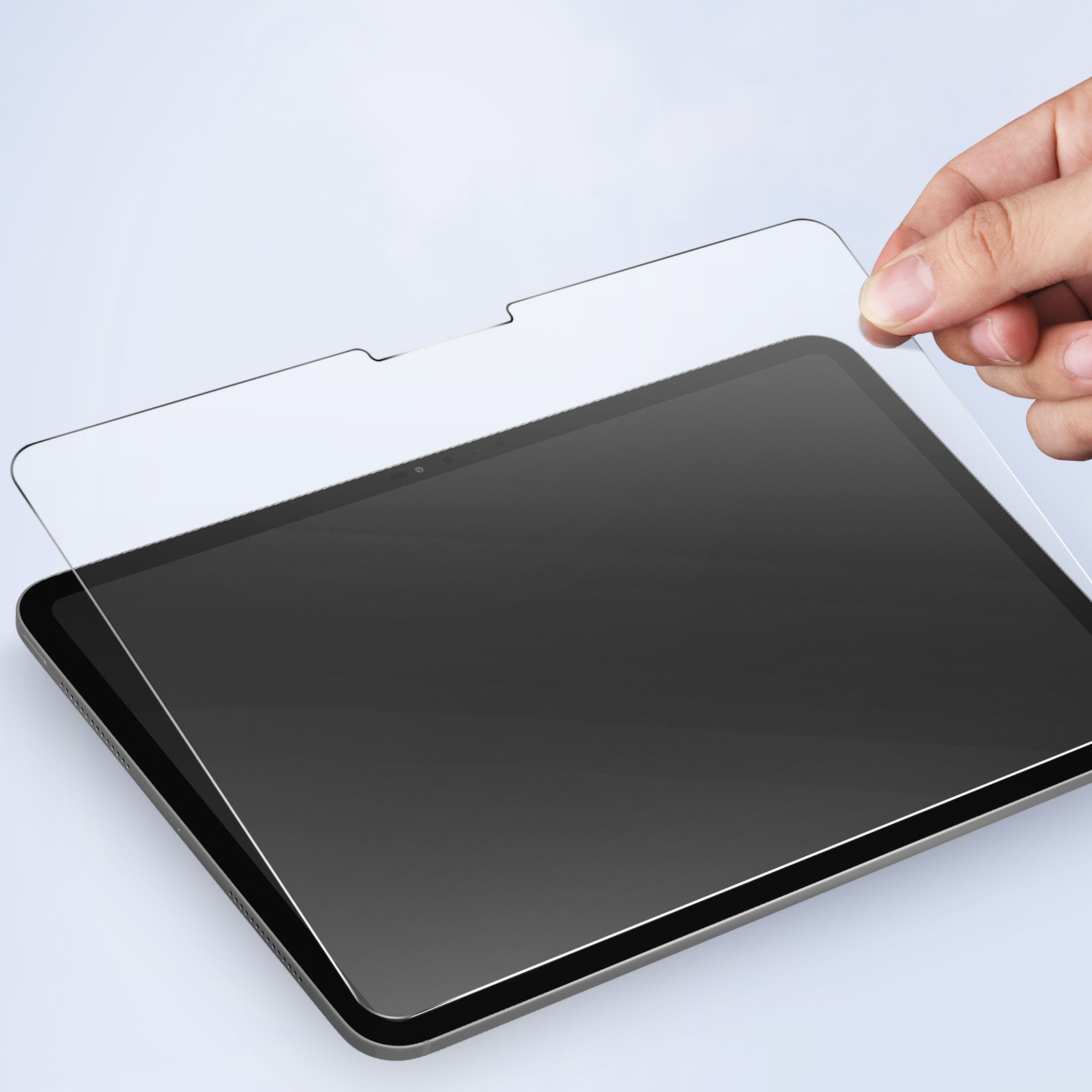 Mano che tiene una protezione schermo trasparente sopra un tablet. Sfondo bianco.