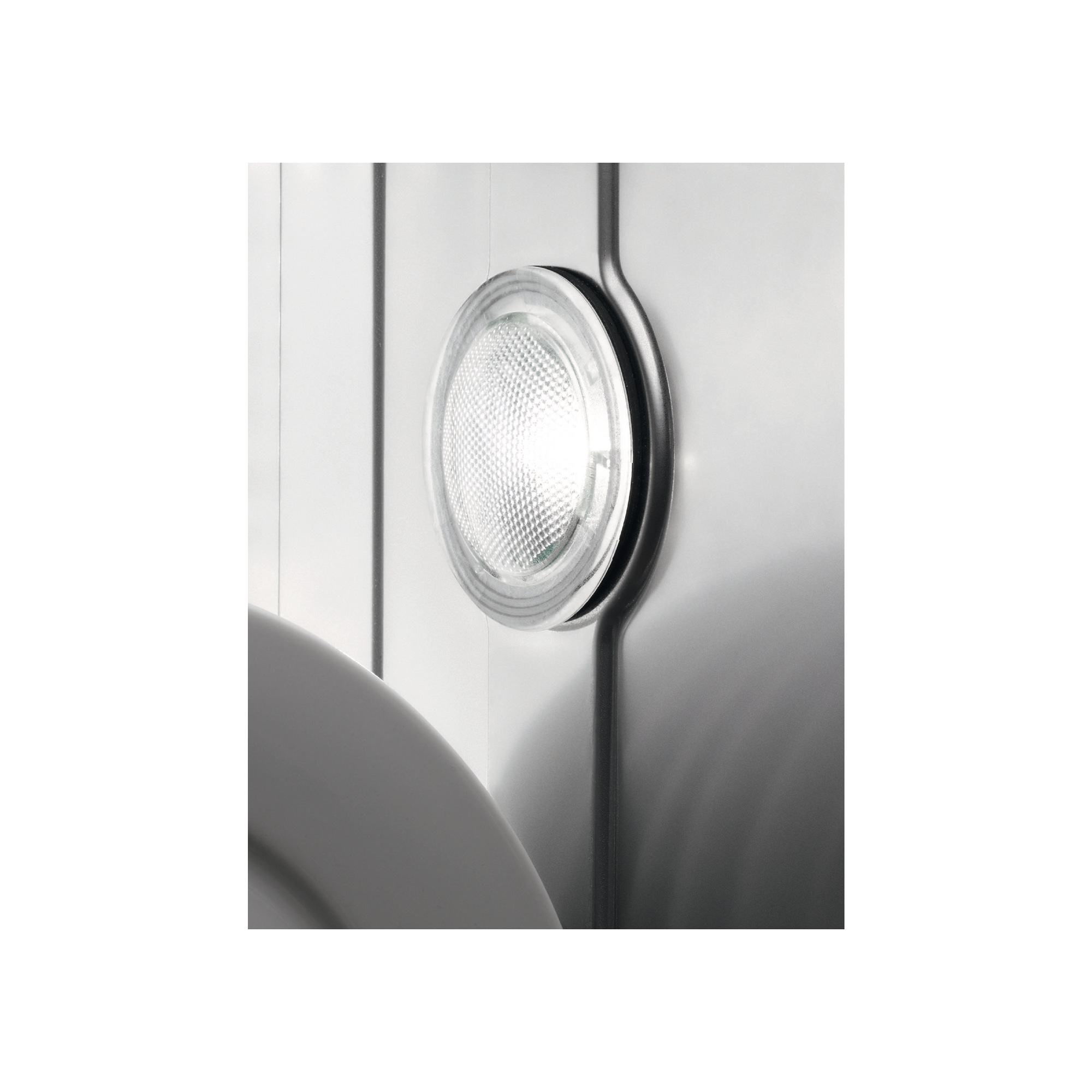 Een close-up van een ronde lamp op een witte muur. Het licht is aan.