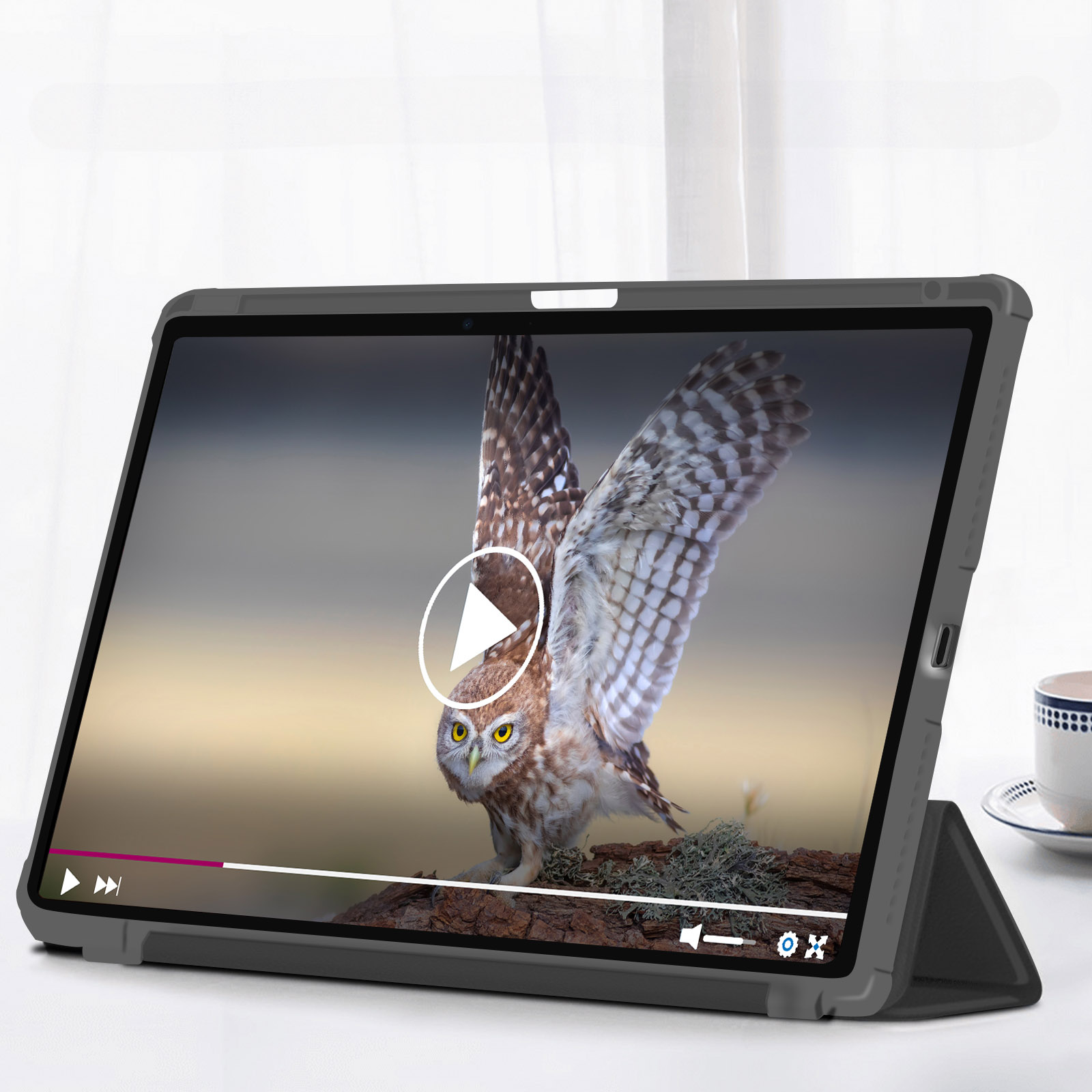 Tablet che riproduce un video di un gufo marrone con le ali spiegate, su un tavolo bianco.