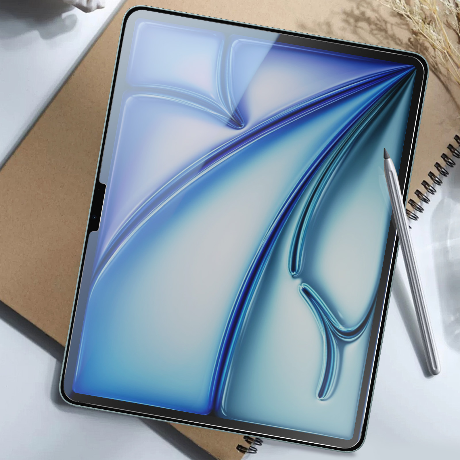 Un tablet con una protezione per lo schermo sopra un taccuino e una penna.