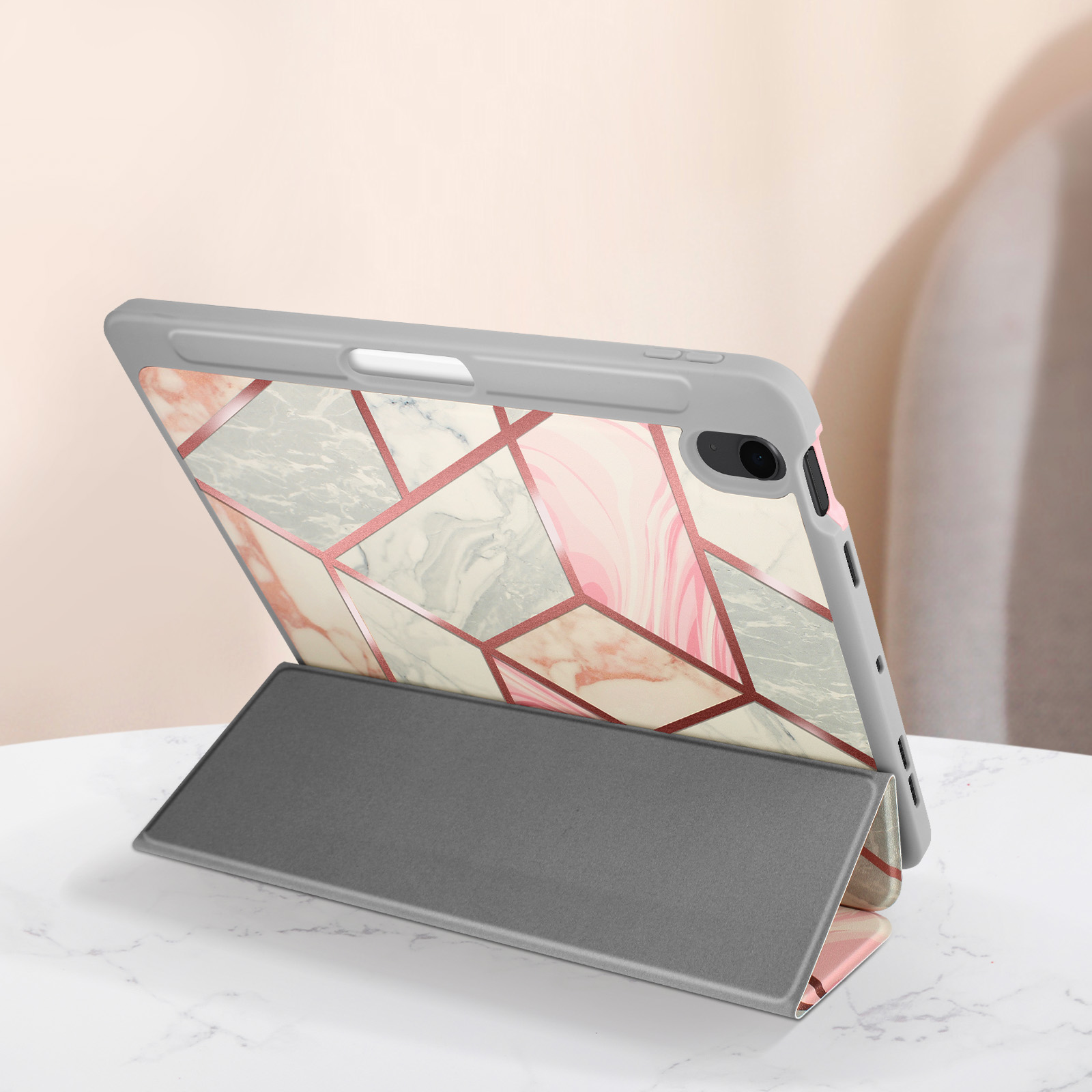 Un tablet con una custodia a fantasia, puntellato. La custodia è grigia con accenti rosa e bianchi.