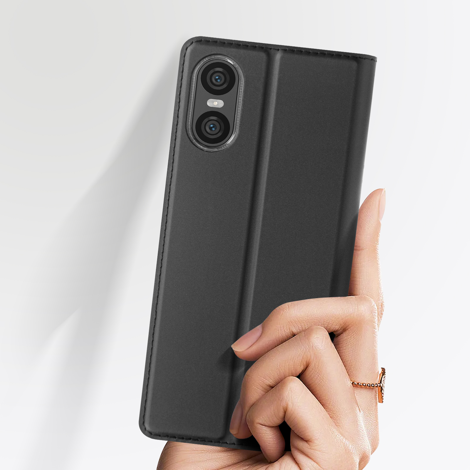 Une main tenant un étui de téléphone noir fermé. L'étui a une texture lisse.