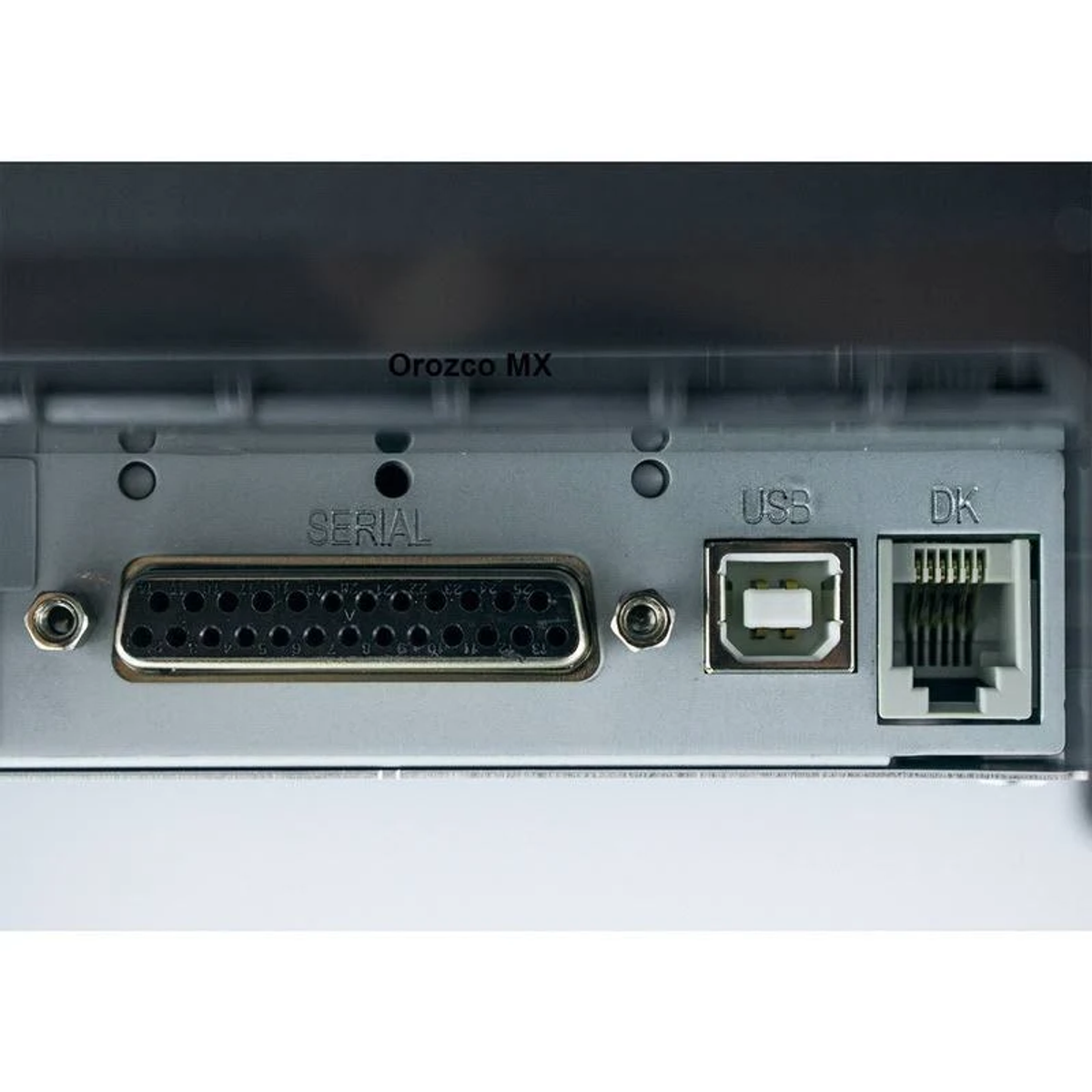 Primer plano de puertos de impresora. Puertos serial, USB y DK en superficie metálica.