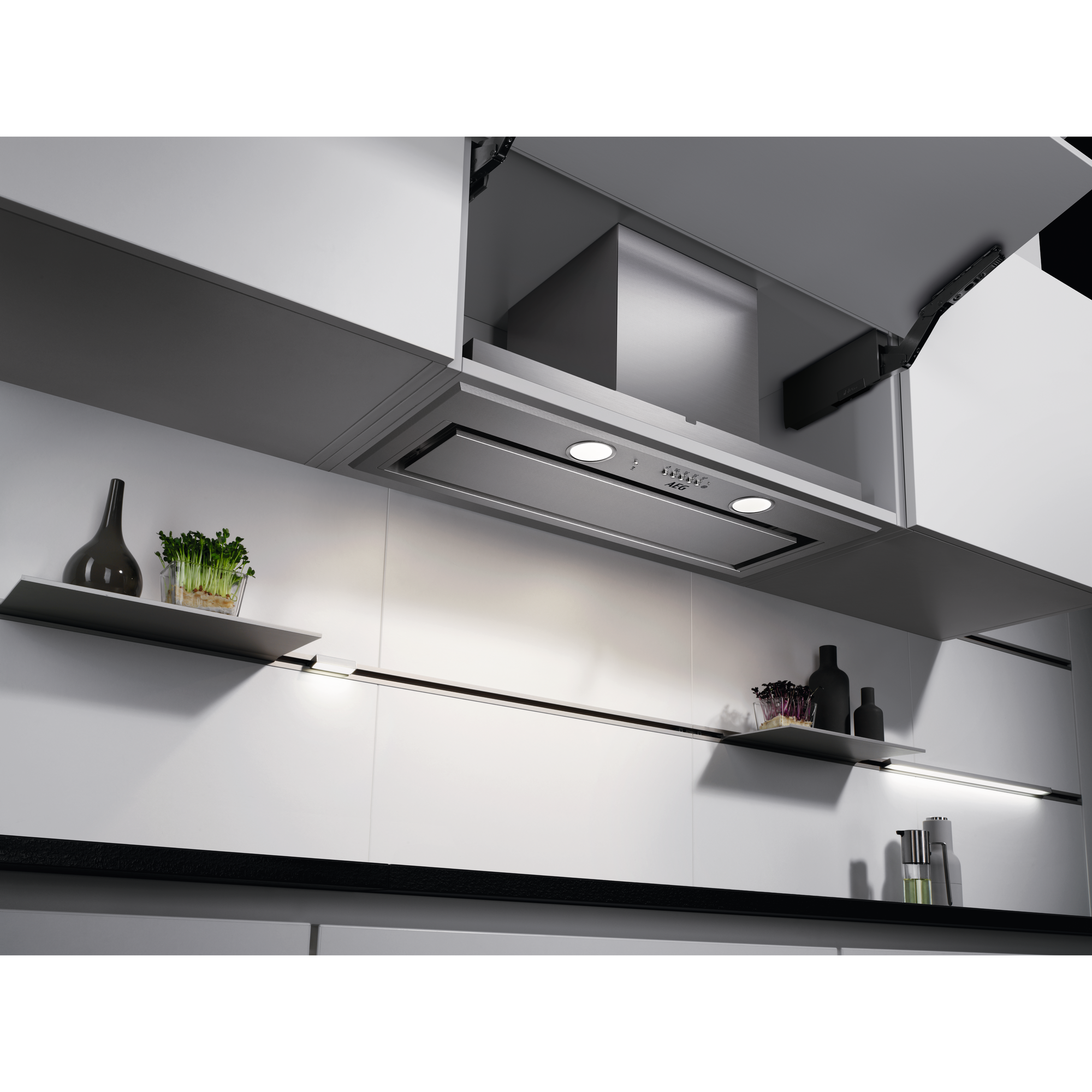 Cappa da cucina con due luci montate in un mobile. Mobile e mensole bianche. Piano di lavoro nero.