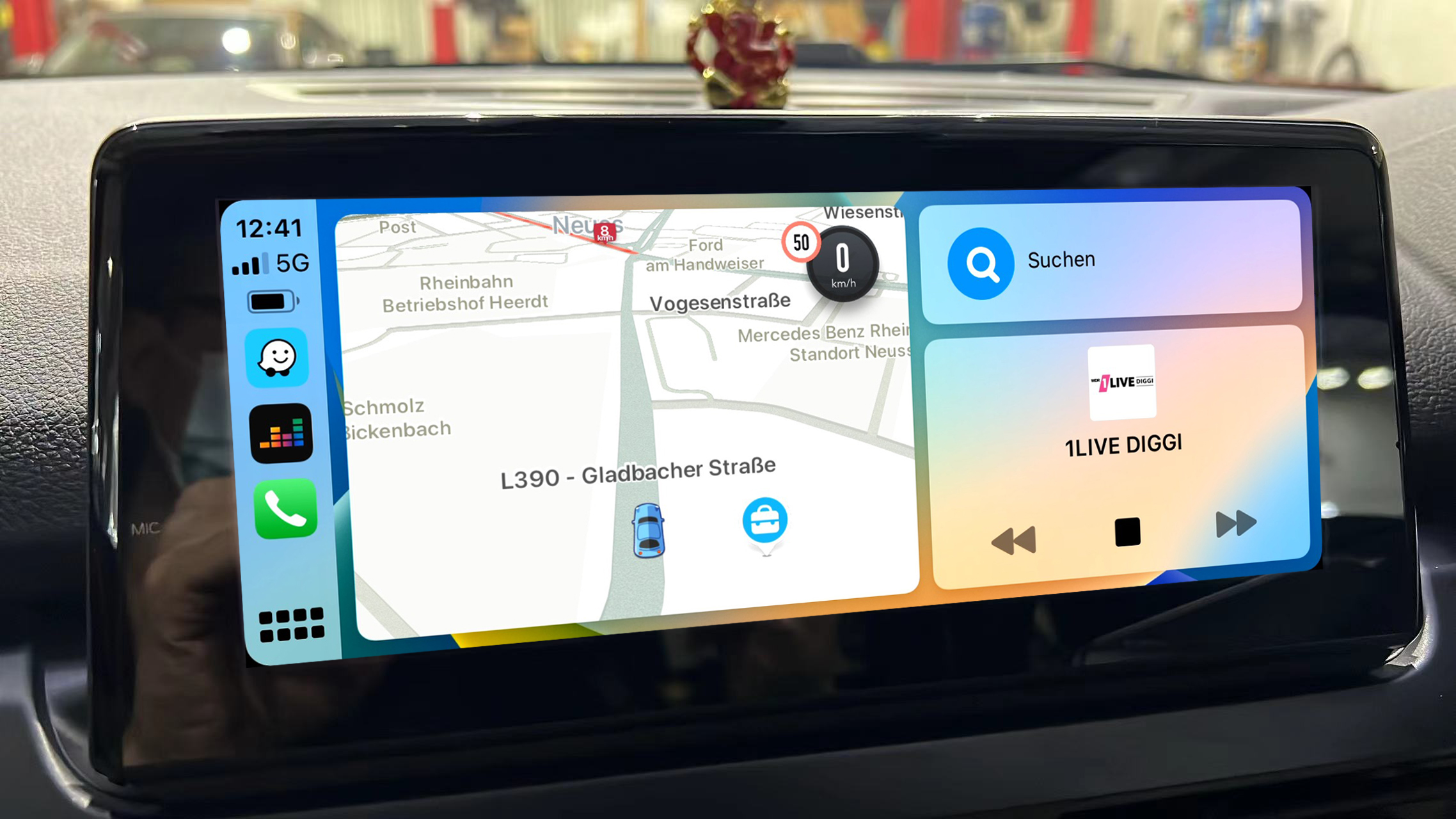 Auto-Armaturenbrett mit Touchscreen, das eine Karte und Musiksteuerungen anzeigt. Zeigt die Apple CarPlay-Oberfläche.