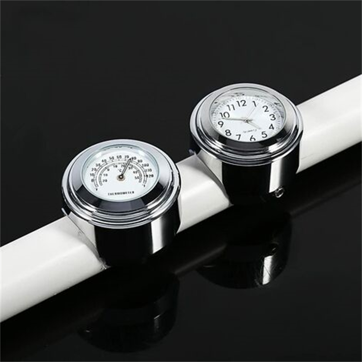 Zwei silbergerahmte Messgeräte auf einem weißen Rohr. Eines ist eine Uhr, das andere ein Thermometer.