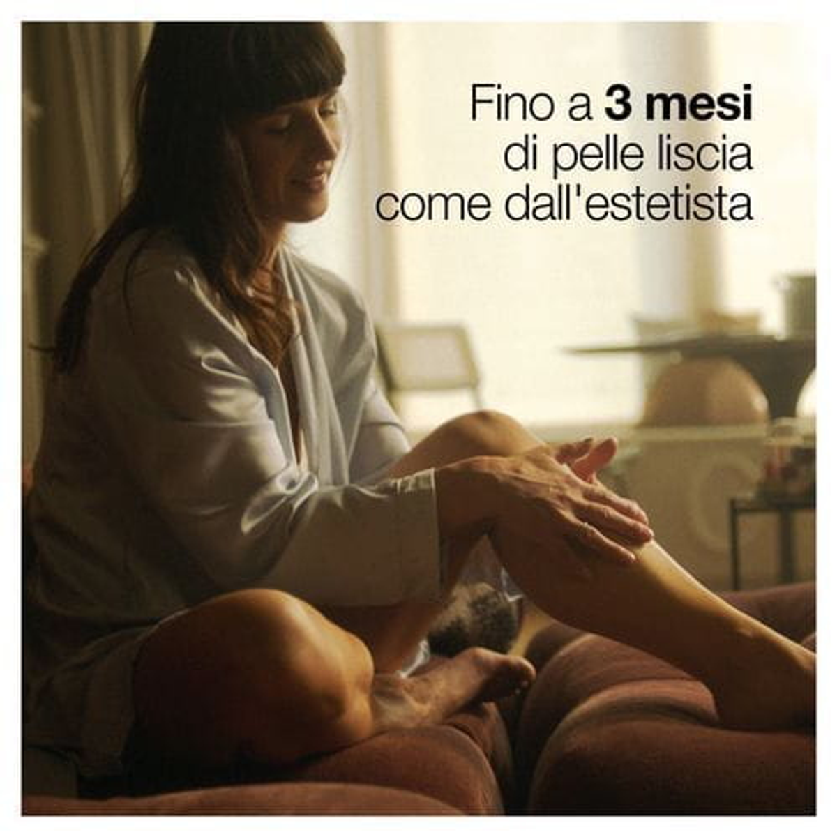 Kobieta nakłada krem na nogę, siedząc na kanapie.