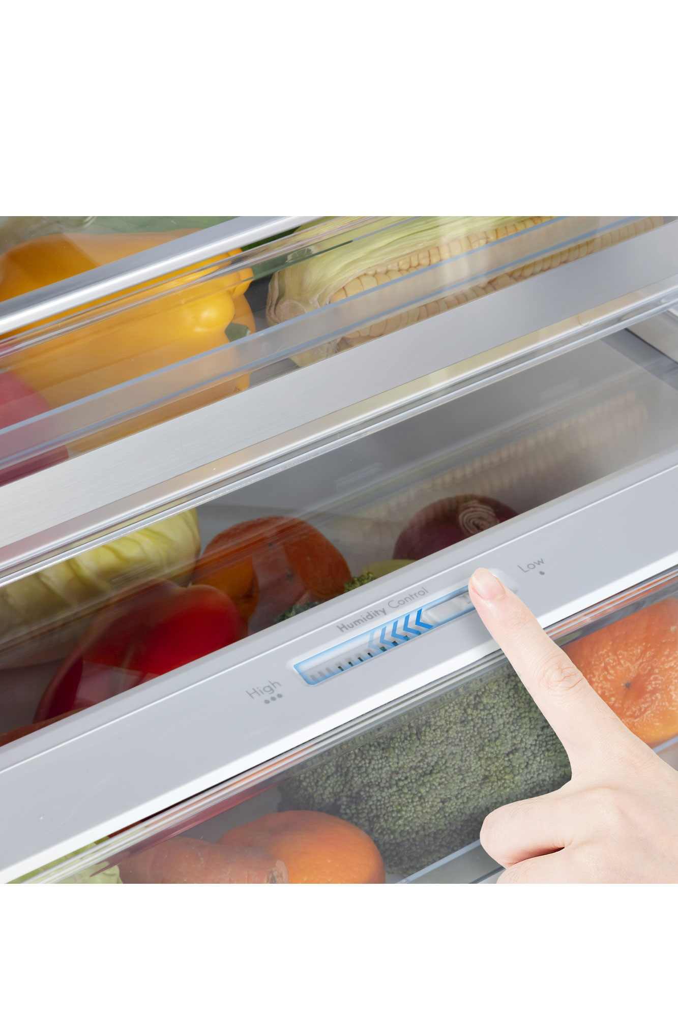 A hand is adjusting the humidity control in a fridge drawer filled with vegetables.