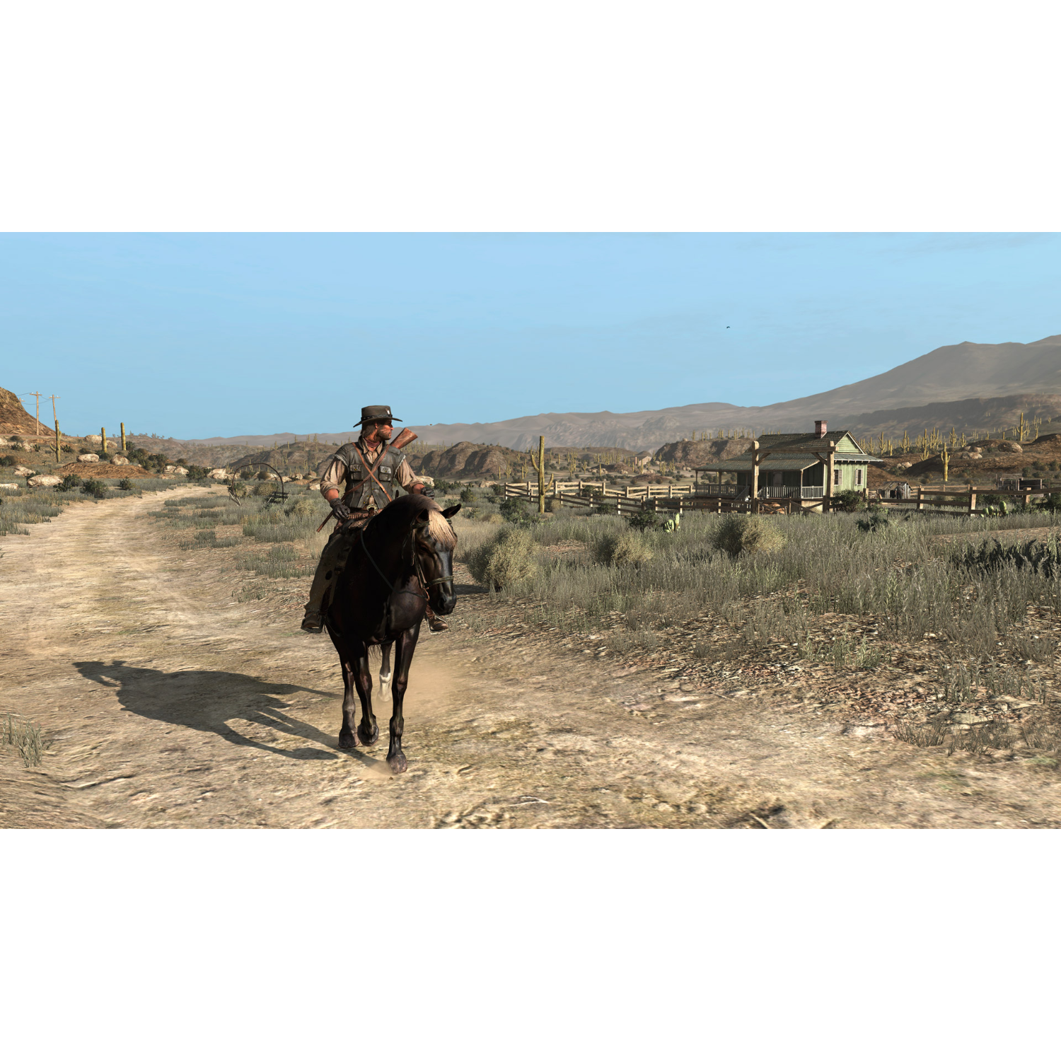 A cowboy rides a black horse on a dirt road towards a house. Mountains and blue sky are in the background.
