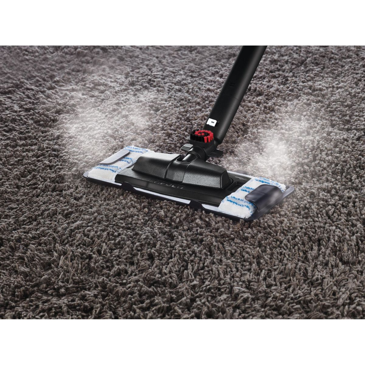 Fregona a vapor limpiando una alfombra marrón, con vapor visible.
