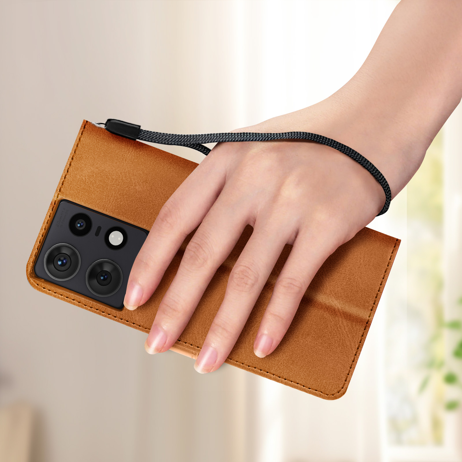La mano di una persona tiene una custodia marrone con un cinturino nero. La custodia ha un'elevazione per la fotocamera.