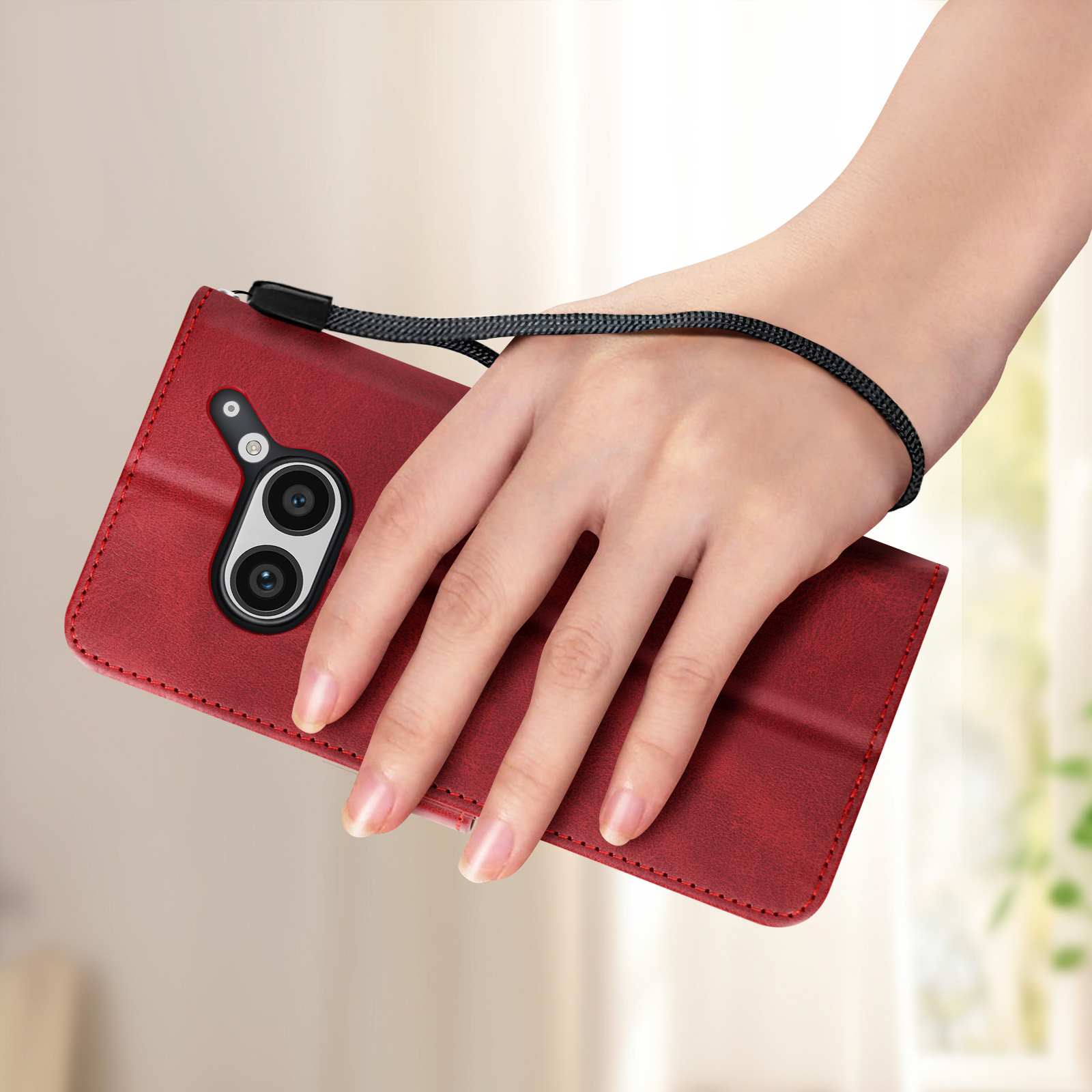 Mano che tiene una custodia rossa per telefono con lenti della fotocamera e cinturino da polso. La custodia ha un aspetto in pelle.