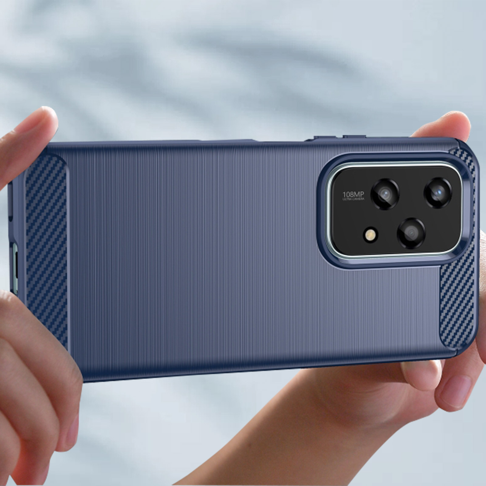 Mani che tengono una custodia blu per telefono. La custodia è strutturata con un design scuro. Lo sfondo è sfocato.