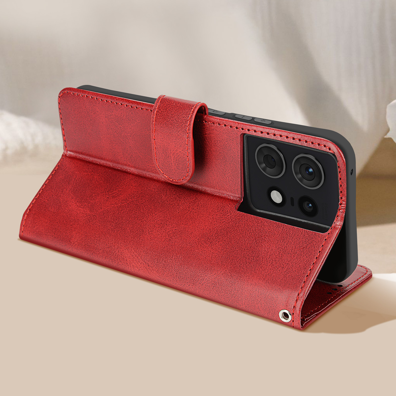Custodia per telefono in pelle rossa piegata per sostenere un telefono. Il telefono è nero e la custodia è su una superficie beige.