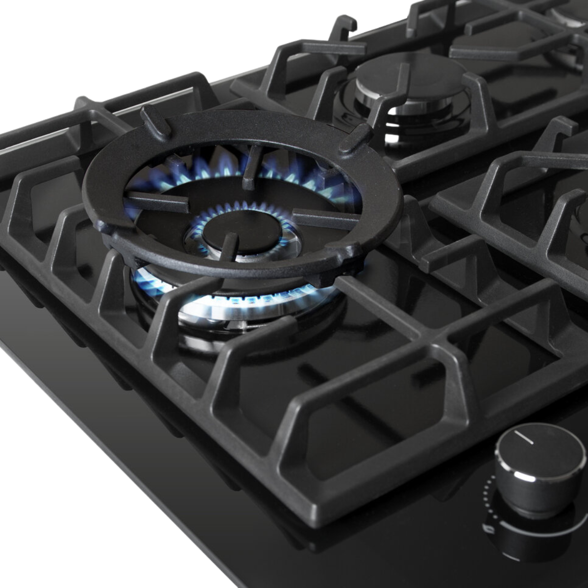 Close-up van een gasbrander met blauwe vlammen. Zwarte kookplaat met zwarte roosters en een zilveren draaiknop.