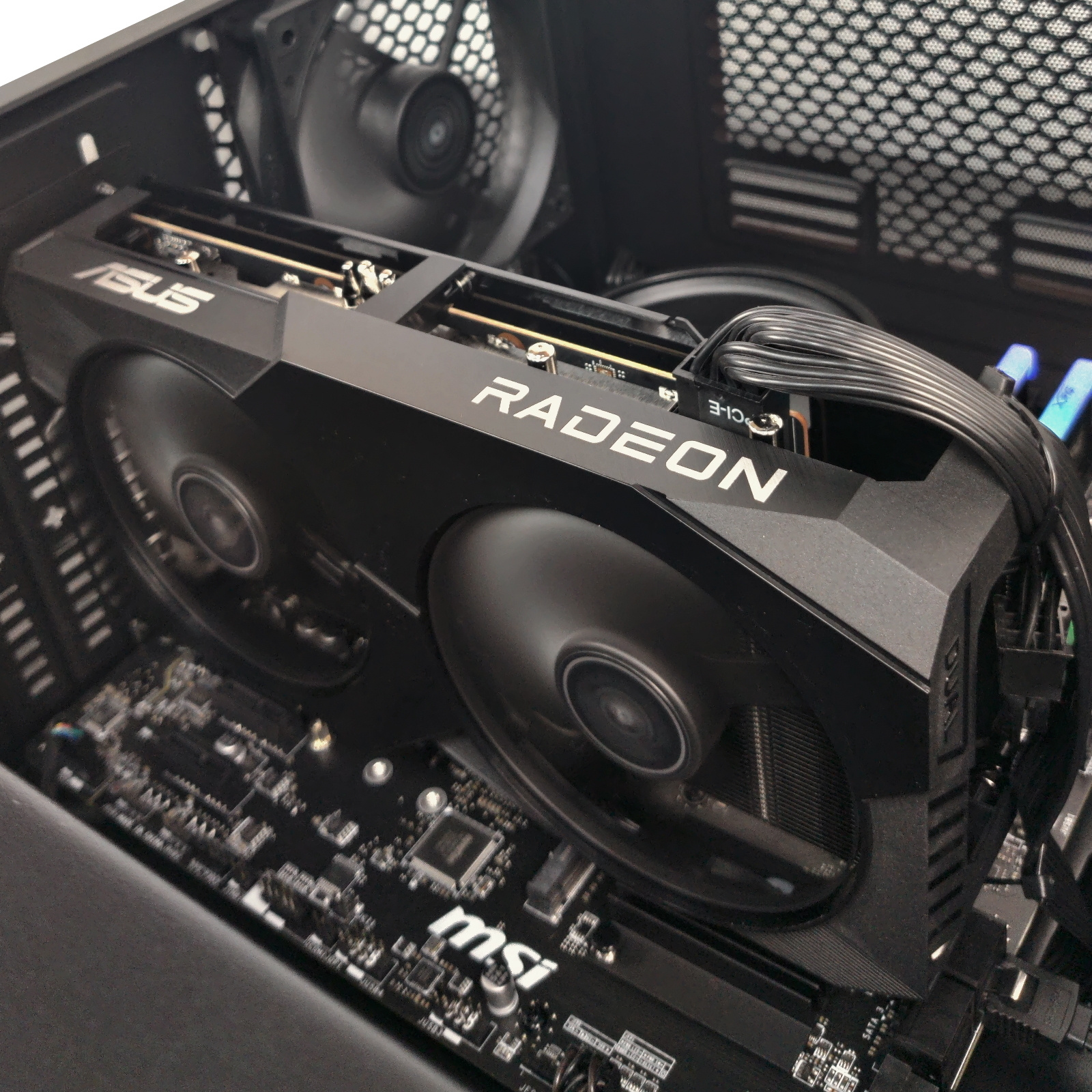 Carcasa de ordenador negra con tarjeta gráfica Radeon, ventiladores y componentes internos visibles.