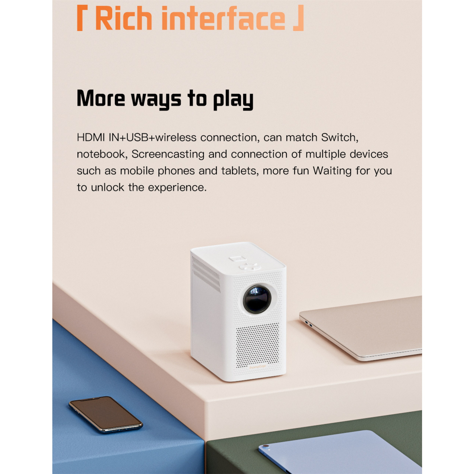 Ein weißer Projektor mit Telefon, Tablet und Laptop auf einer Oberfläche. Text: Rich Interface, mehr Spielweisen.