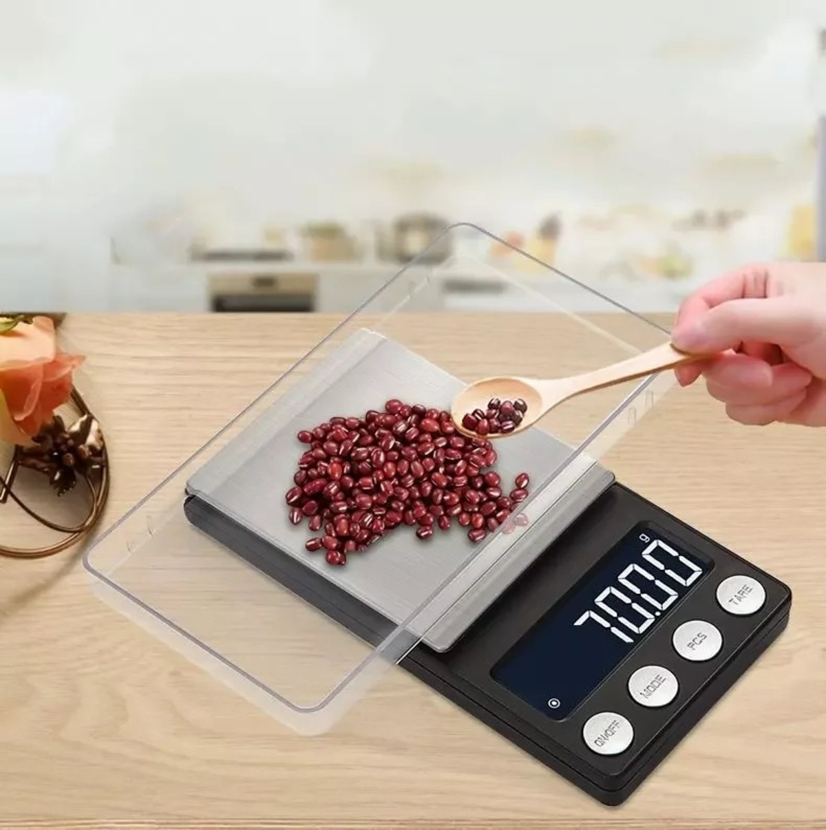 Digitalwaage mit einer Schüssel mit roten Bohnen. Ein Holzlöffel ist in der Schüssel.