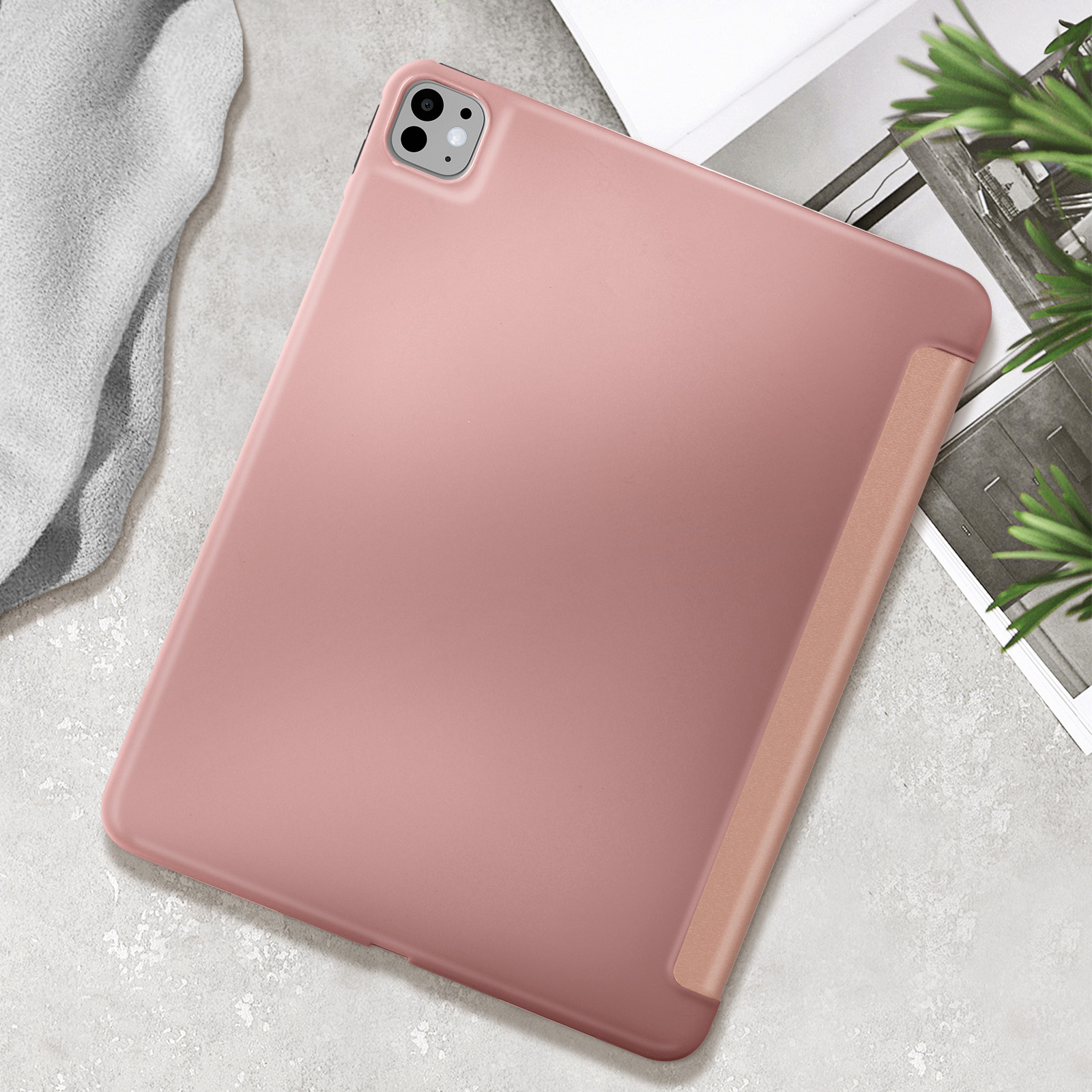 Custodia per tablet rosa. Mostra un tablet con custodia su uno sfondo grigio chiaro. Una pianta è visibile nel fotogramma.
