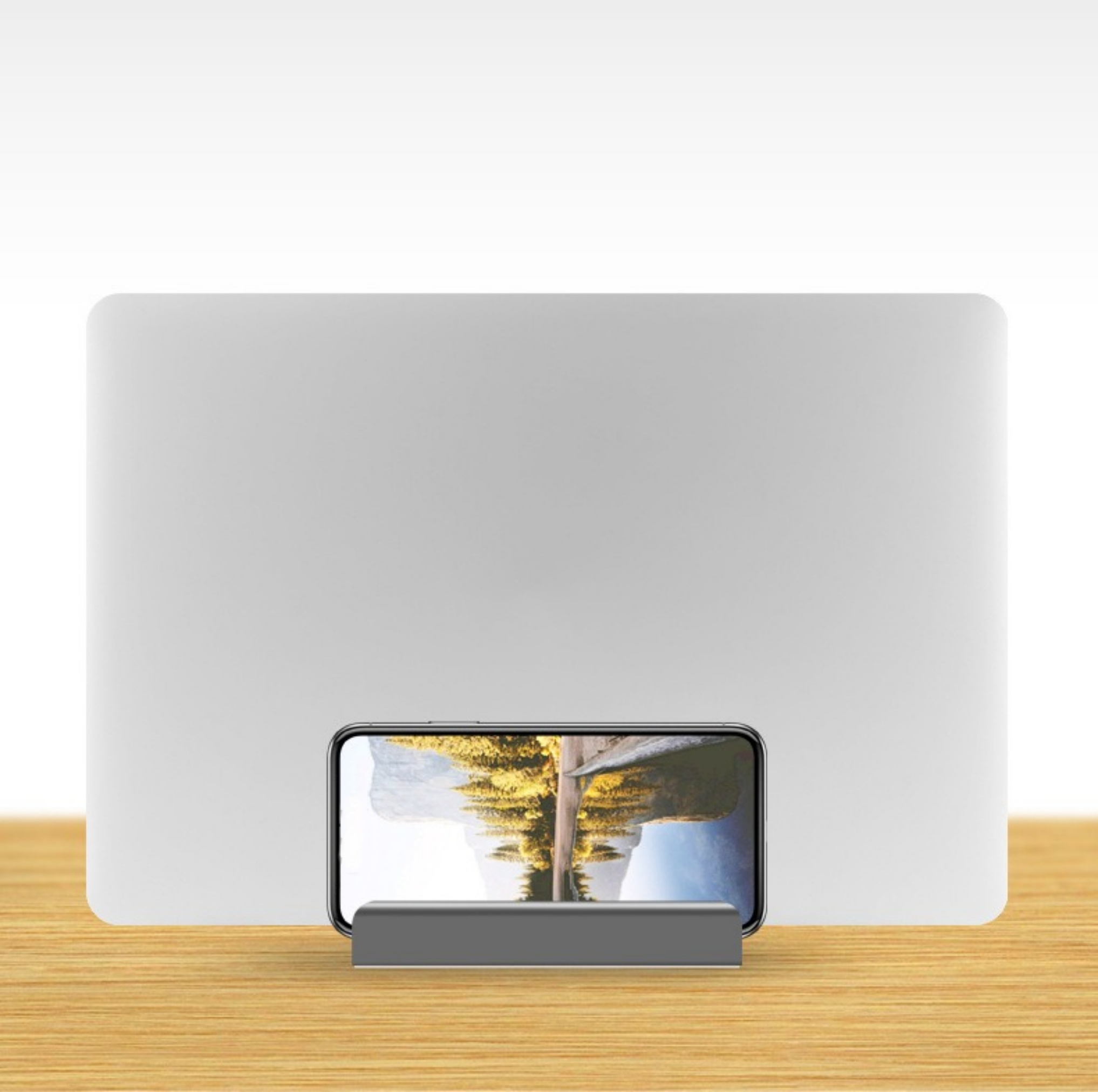 Ein Laptop steht hinter einem Telefonhalter mit einem Telefon, das ein Landschaftsbild zeigt. Die Szene ist auf einem Holztisch.