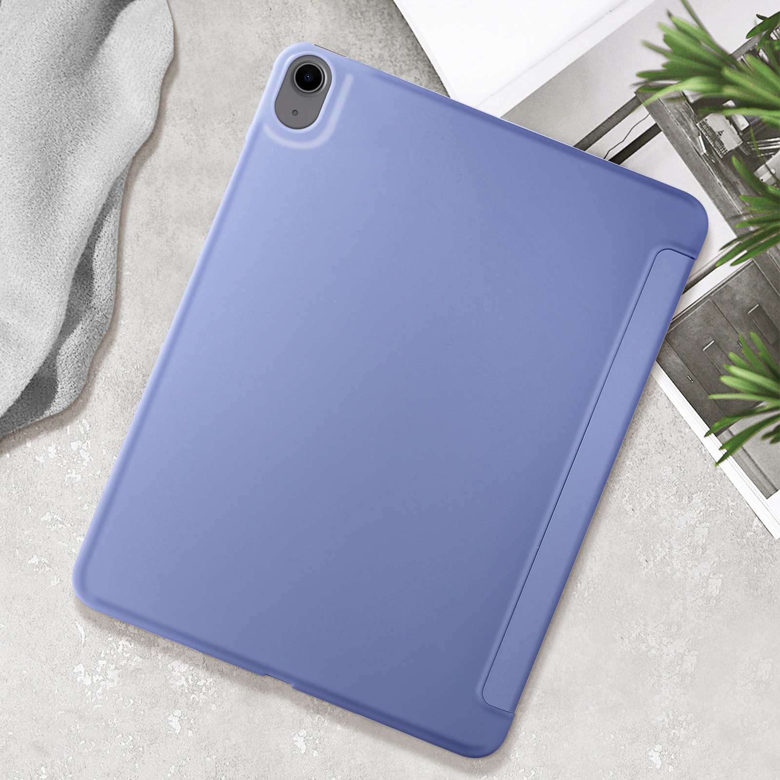 Tablet blu con custodia, appoggiato su una superficie strutturata con un panno grigio e una pianta.