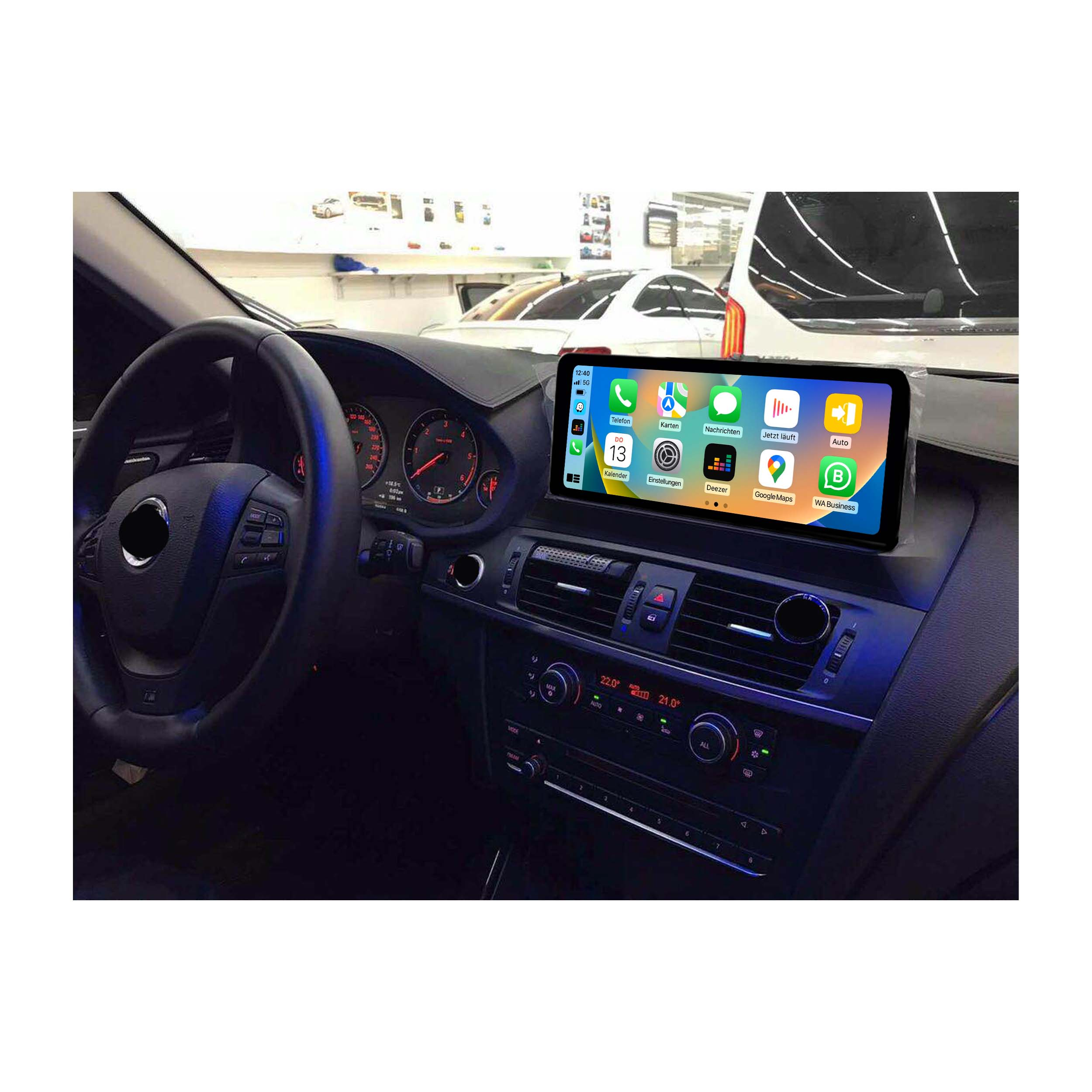 Autointerieur mit Bildschirm, der App-Symbole anzeigt. Lenkrad ist sichtbar. Hintergrund: andere Autos.