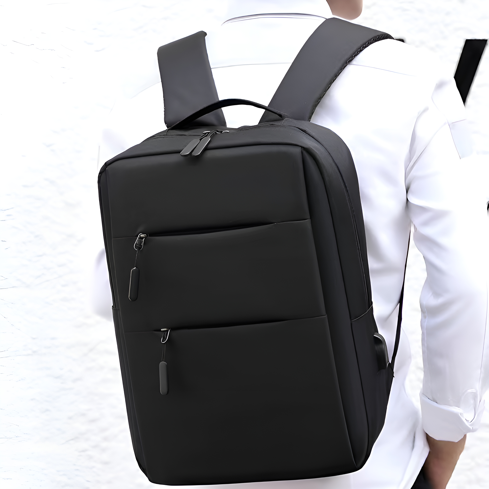 Mann mit schwarzem Rucksack, von hinten vor weißer Wand gesehen.