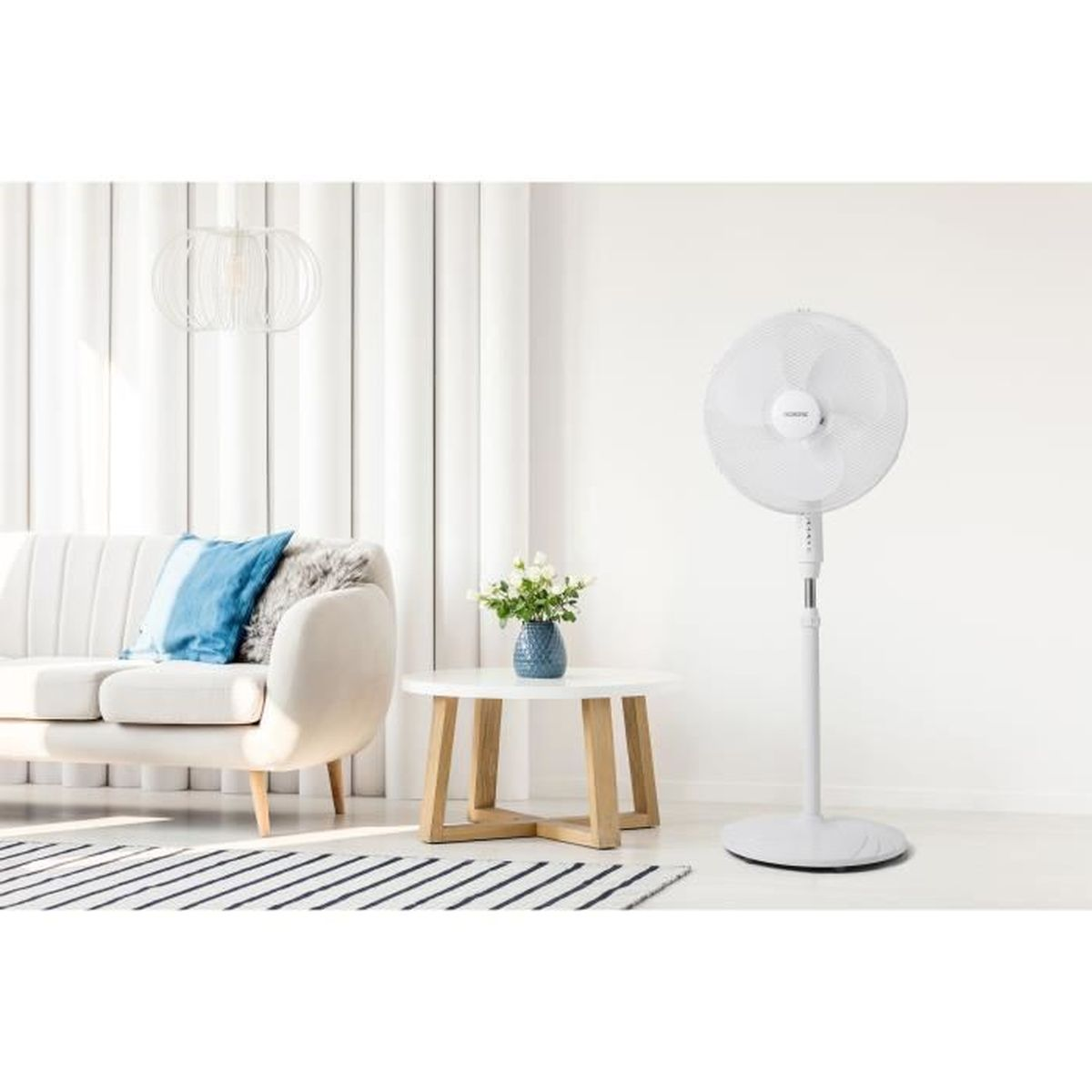 Un ventilatore da terra bianco è accanto a un divano e un tavolo.