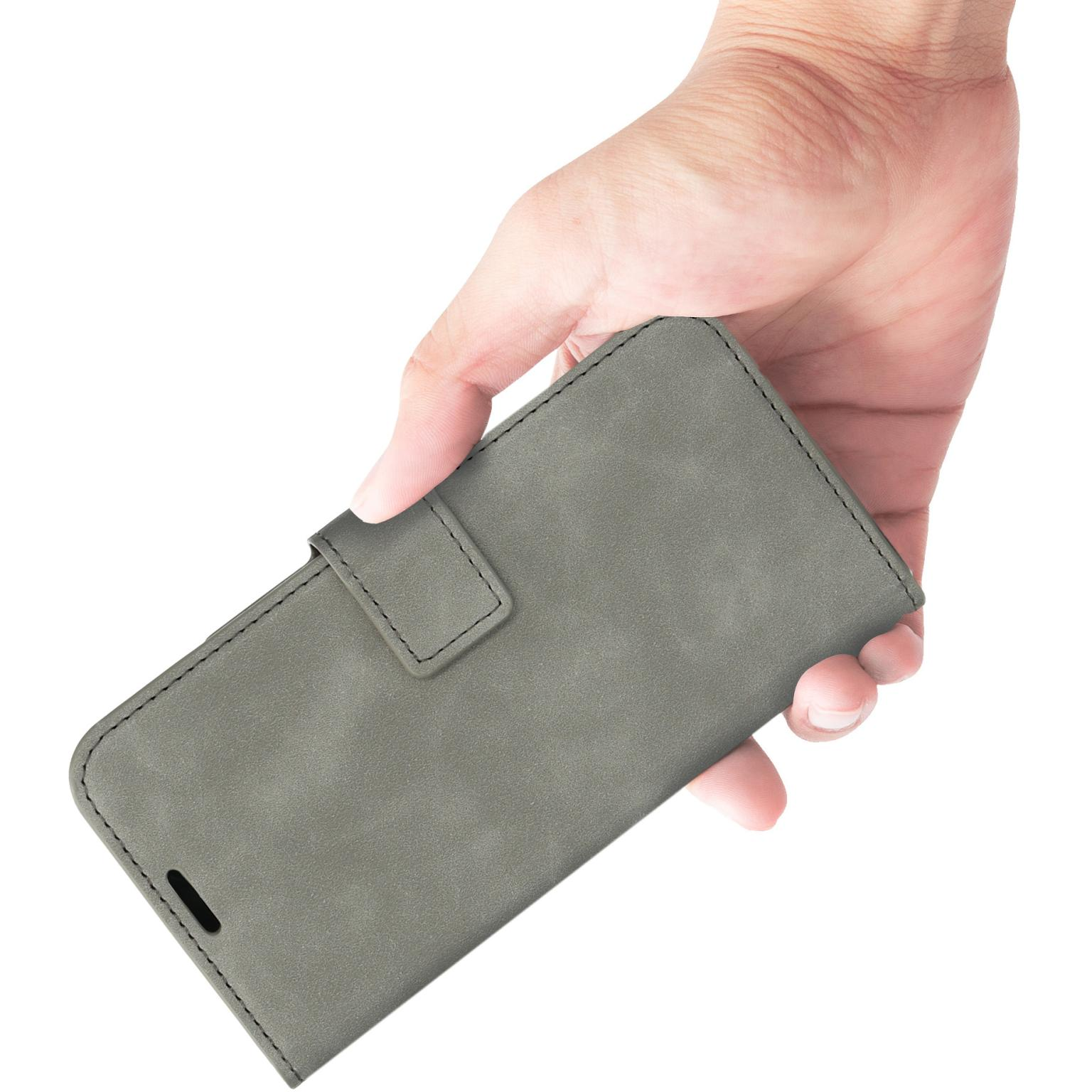 Een hand houdt een grijze telefoonhoes vast. De hoes is gesloten, met stikseldetails. Lichte achtergrond.
