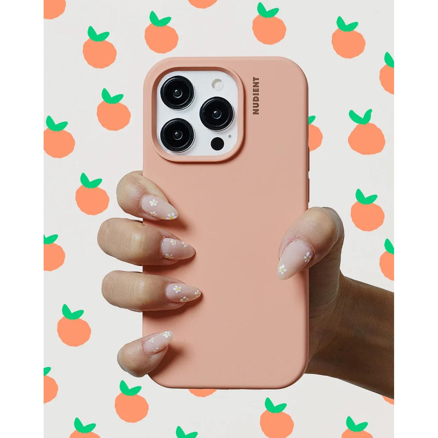 A hand holds a pink phone case with a white and orange background with orange fruit.