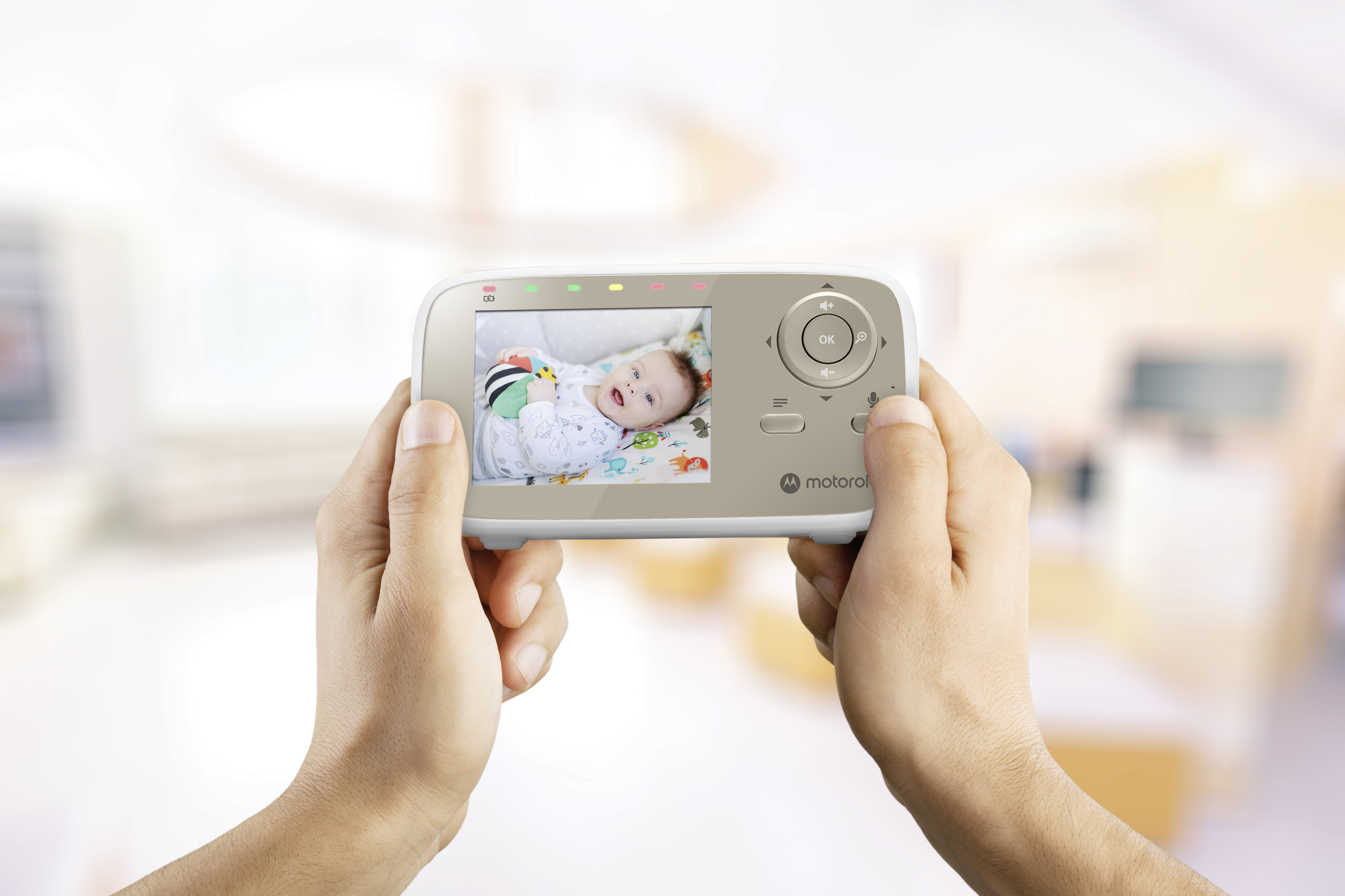 Babyphone in Händen gehalten. Zeigt ein Baby in einem Kinderbett auf dem Bildschirm. Der Hintergrund ist unscharf.