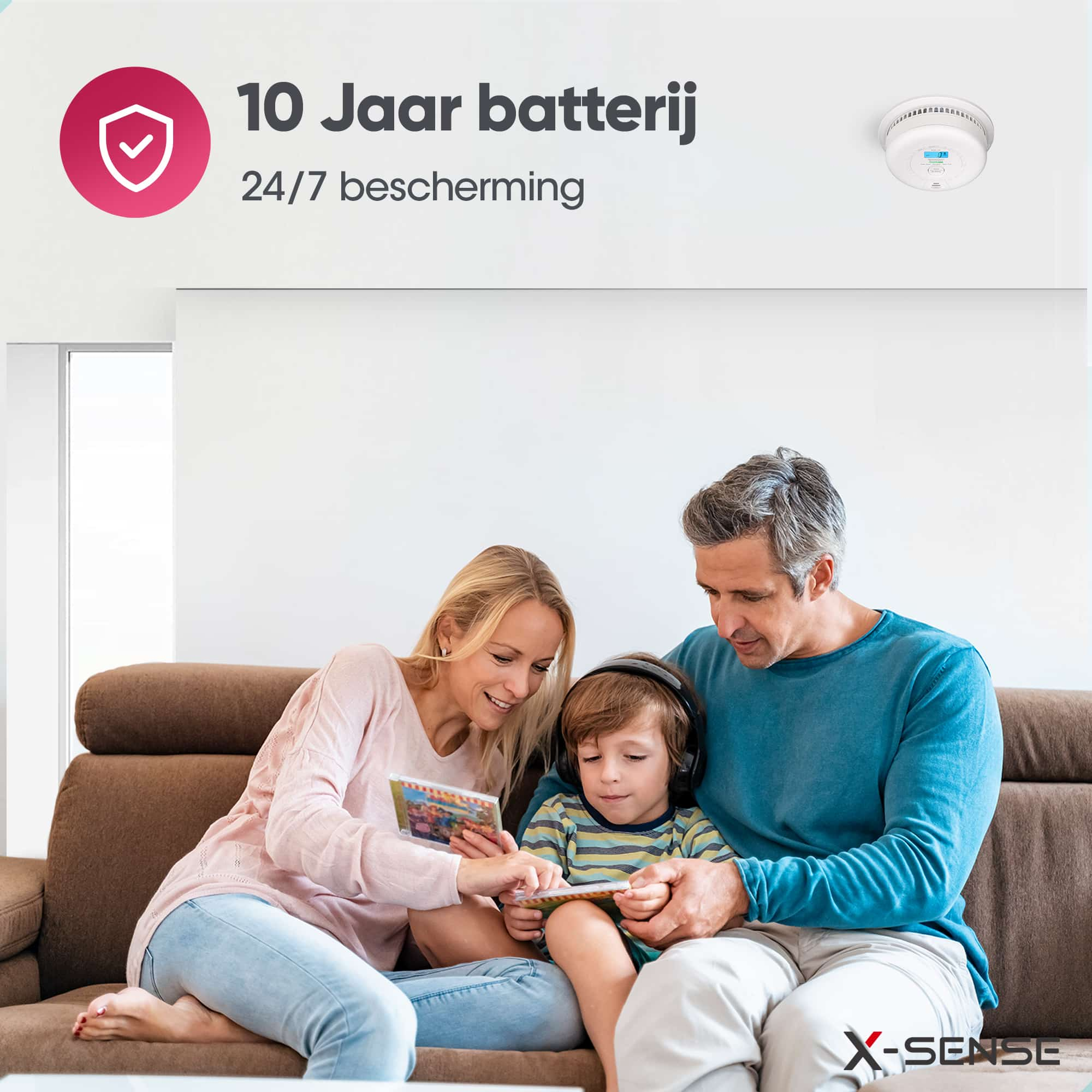 Familie auf dem Sofa, liest Buch und schaut auf einen Rauchmelder.