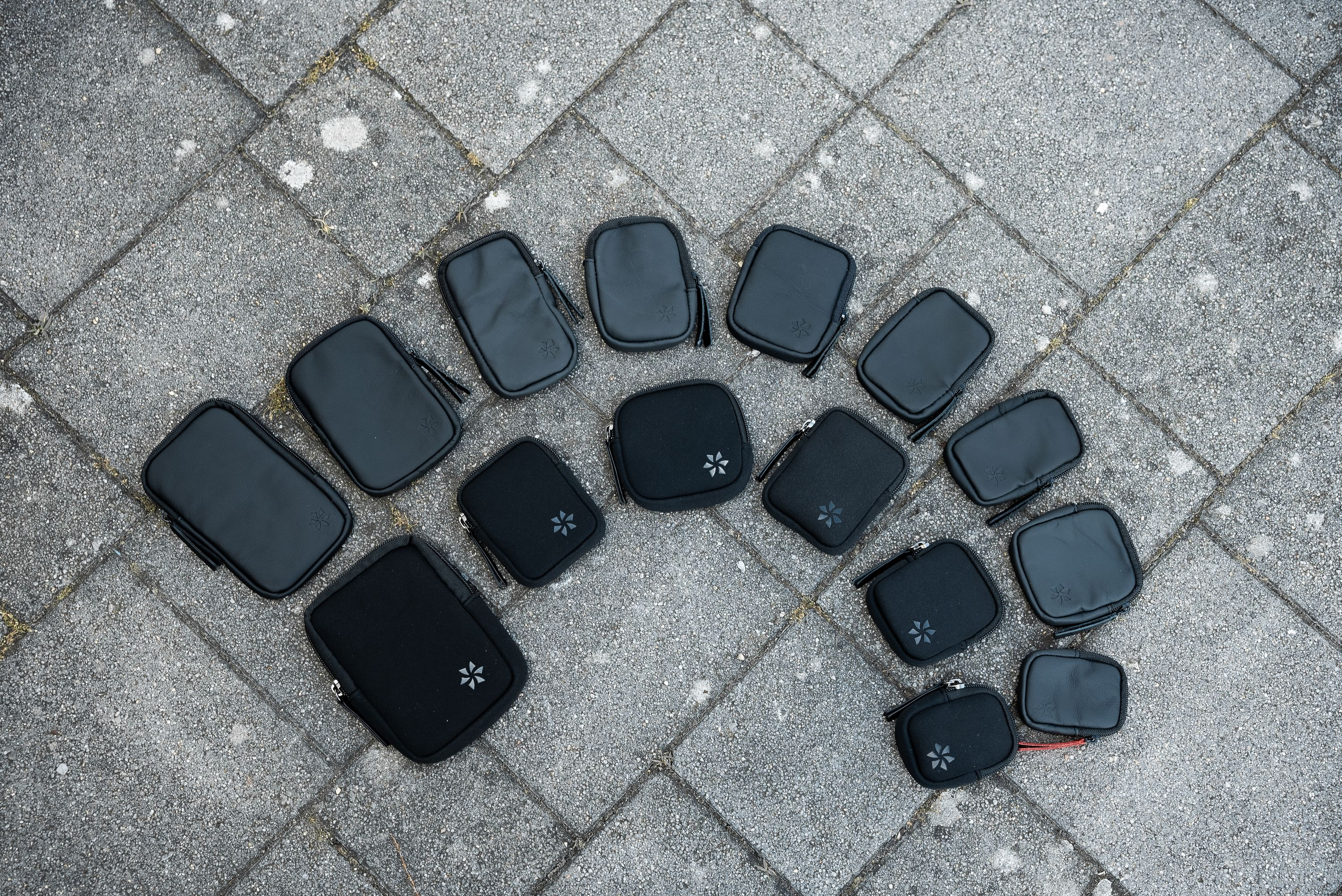 Draufsicht auf mehrere kleine schwarze Beutel, die auf einer grauen, strukturierten Oberfläche angeordnet sind.