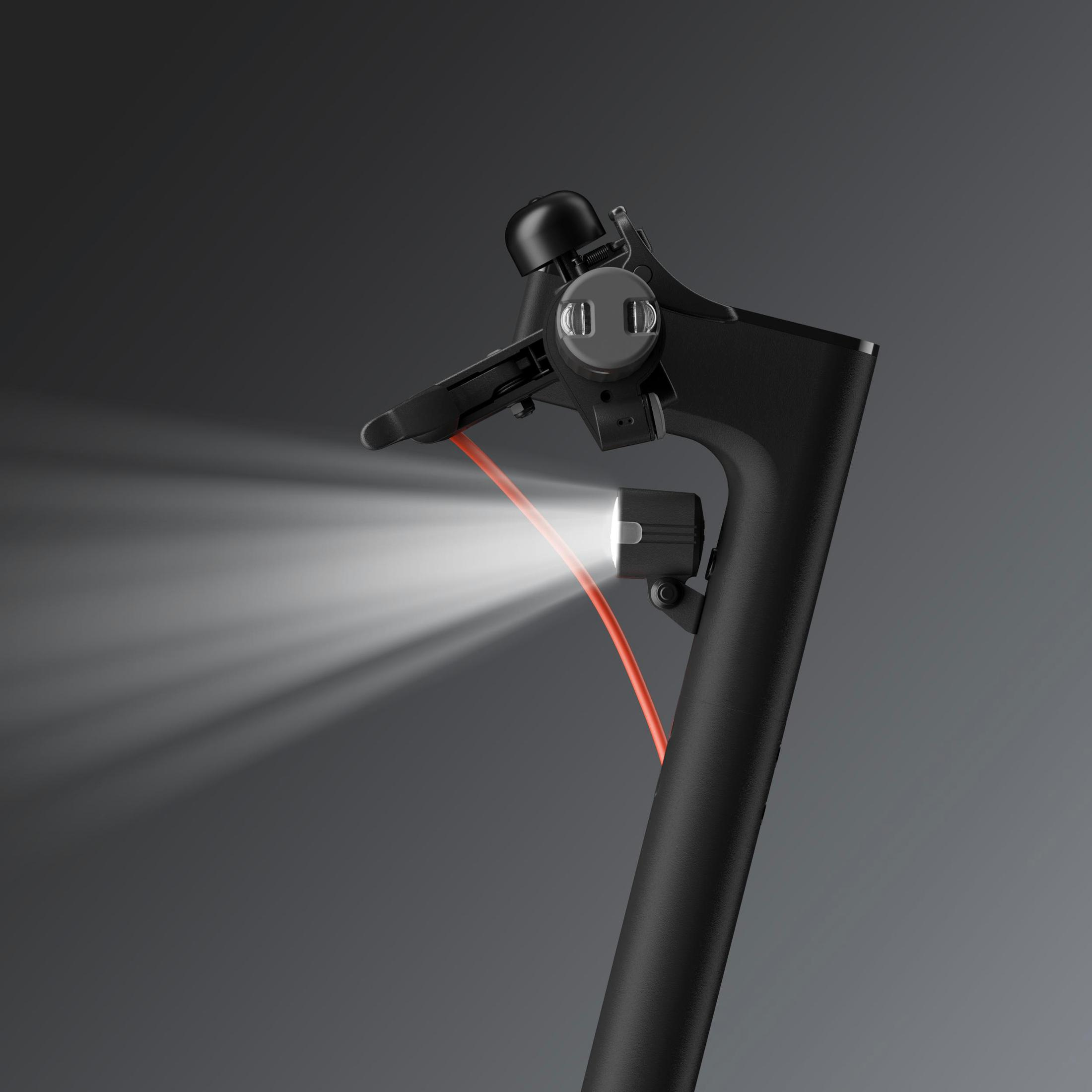 Zbliżenie czarnej kierownicy skutera z jasnym, białym reflektorem świecącym do przodu.