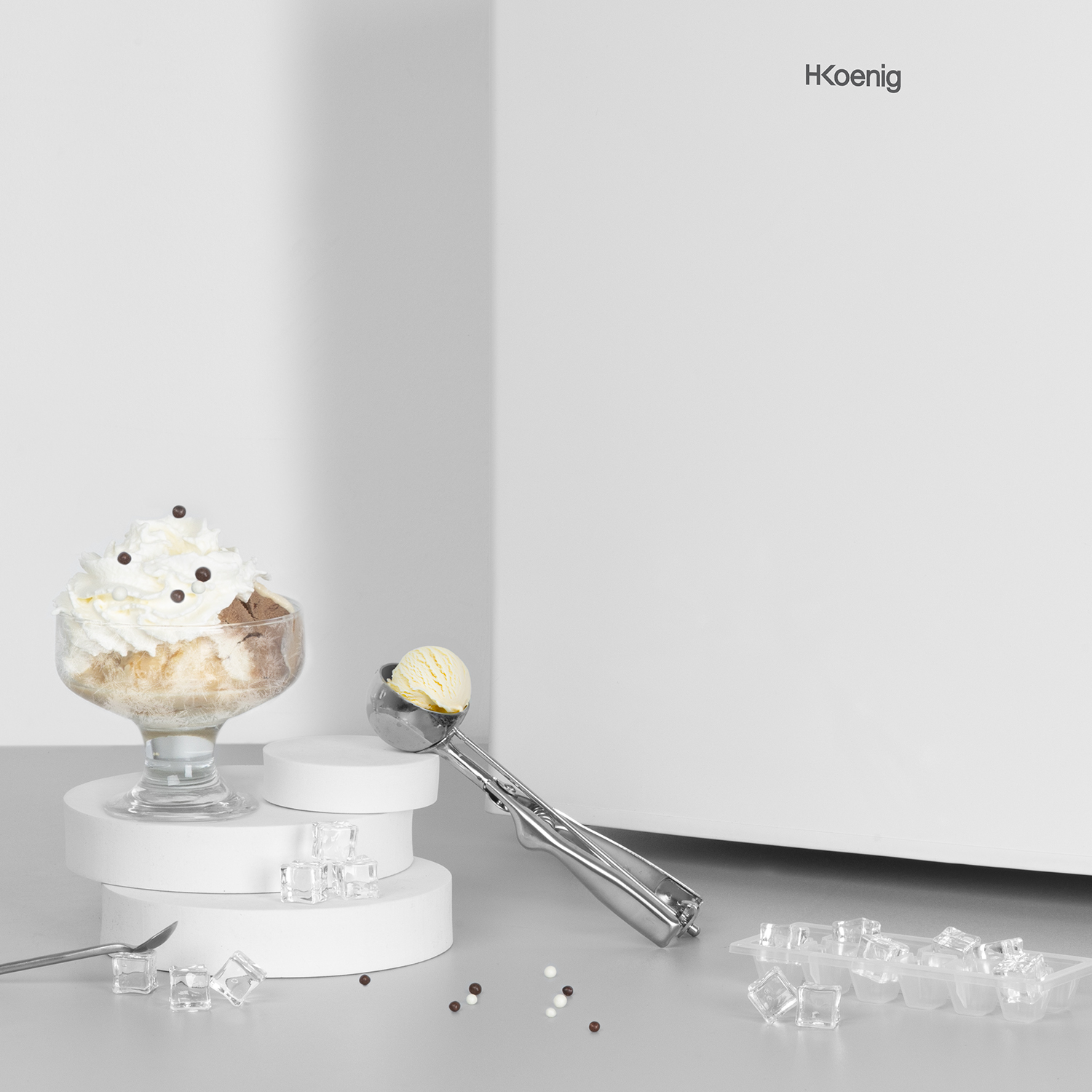 Coppa gelato, paletta per gelato e cubetti di ghiaccio, sfondo bianco.