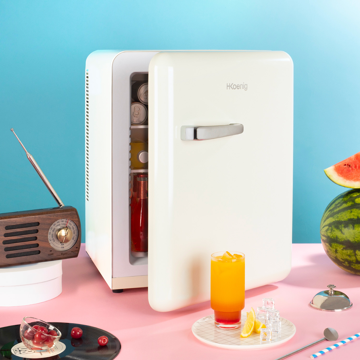 Mini-frigo bianco aperto, bevande dentro, con radio e decorazioni.