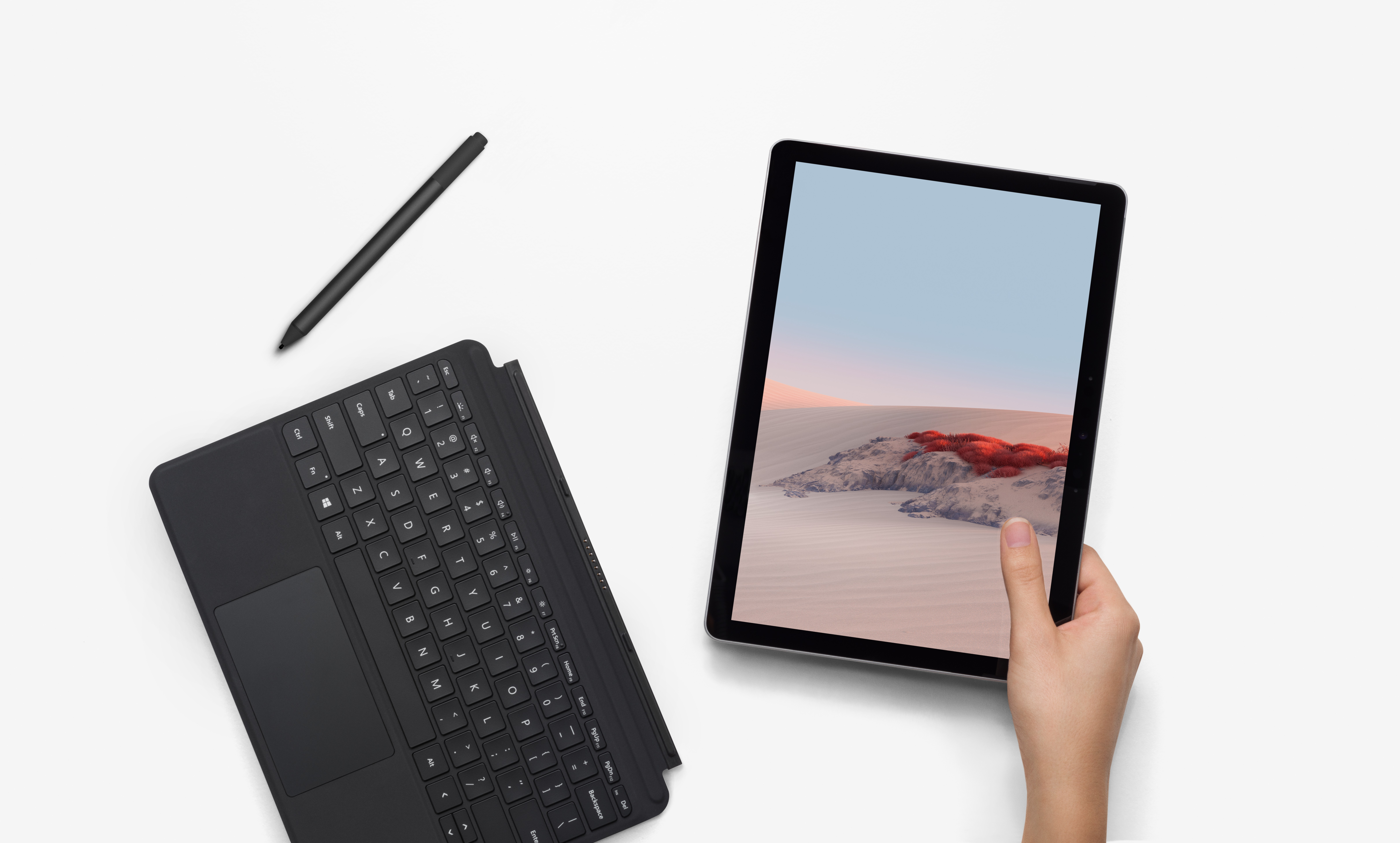 Tablet, tastiera e penna su superficie bianca. Lo schermo mostra un paesaggio desertico.