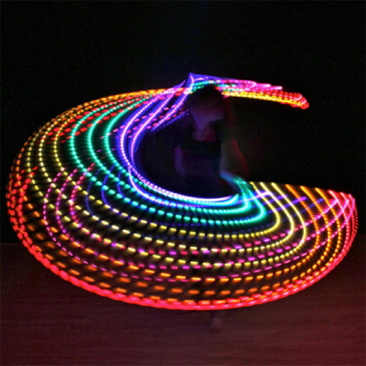 Person, die im Dunkeln einen leuchtenden, bunten Hula-Hoop dreht.