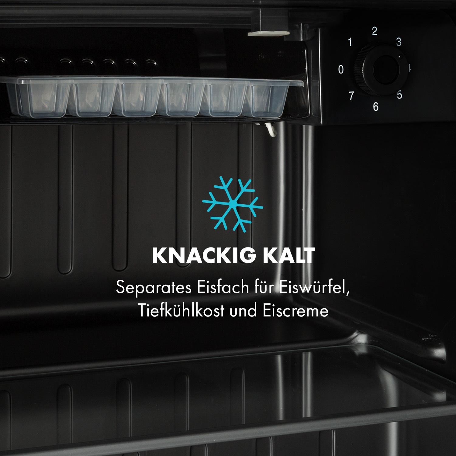 Innenraum eines schwarzen Minikühlschranks mit Eiswürfelschale. Text sagt: 'Knackig kalt'.