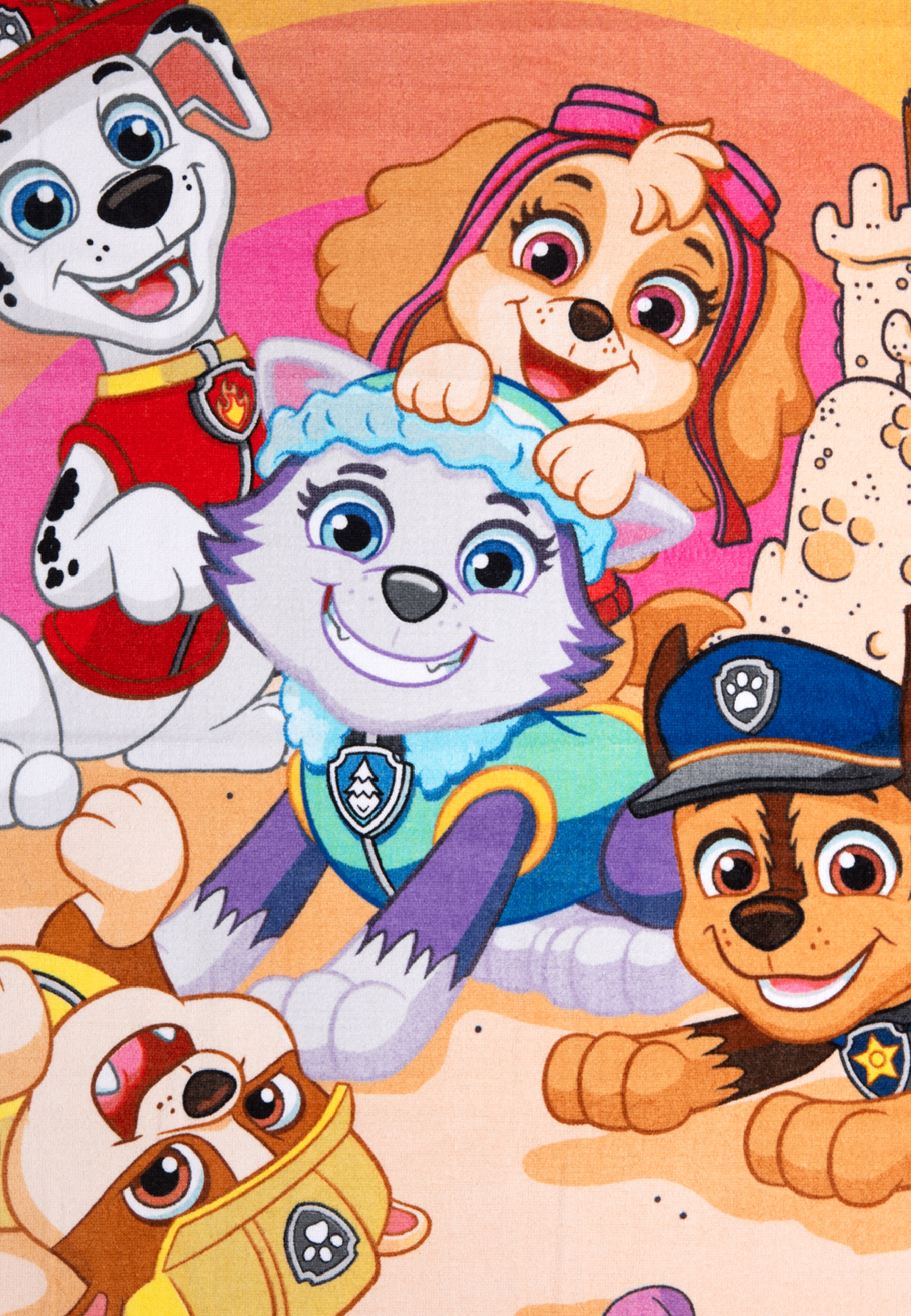 Zeigt die Welpen von Paw Patrol am Strand mit Sandburgen im Hintergrund.