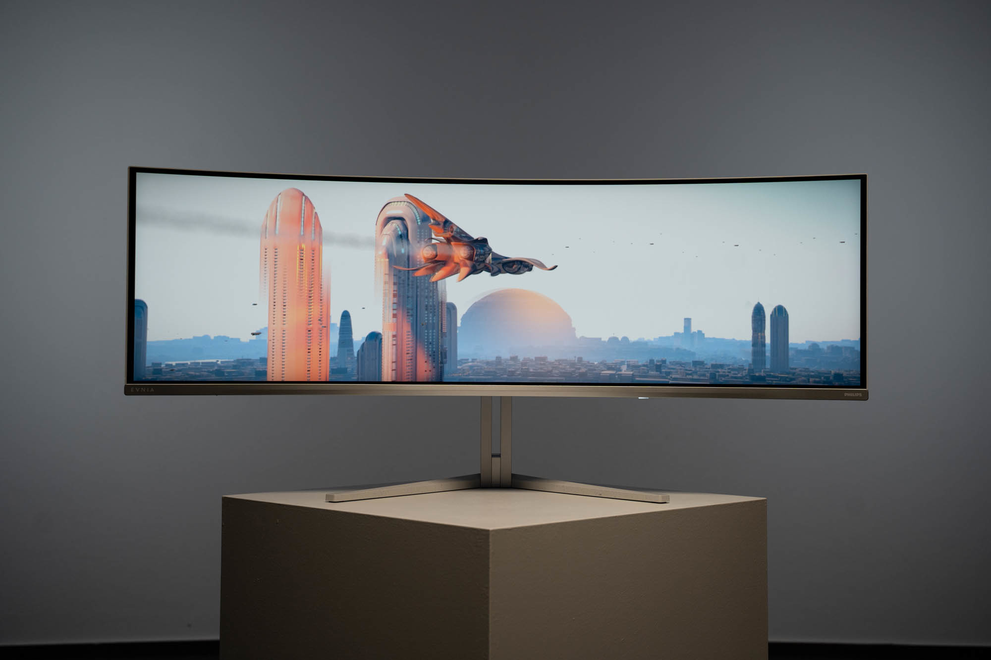 Monitor curvo mostra una scena urbana futuristica con un veicolo volante.