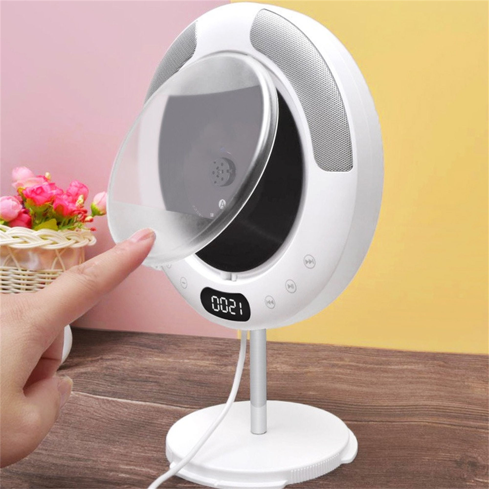 Ein weißer CD-Player mit durchsichtiger Abdeckung und eine Hand, die die Abdeckung berührt, wird gezeigt.