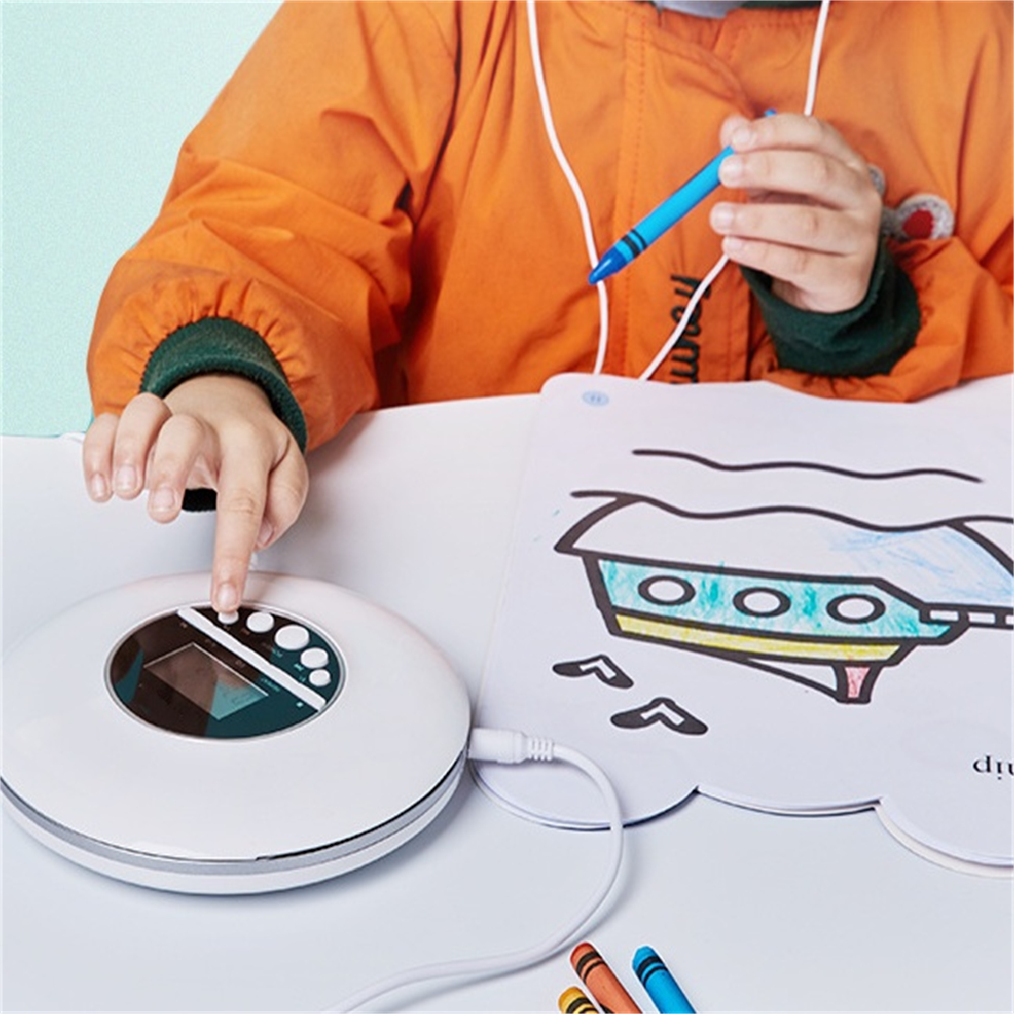 Ein weißer CD-Player mit einem Kind, das mit Buntstiften zeichnet. Das Bild zeigt ein Boot.