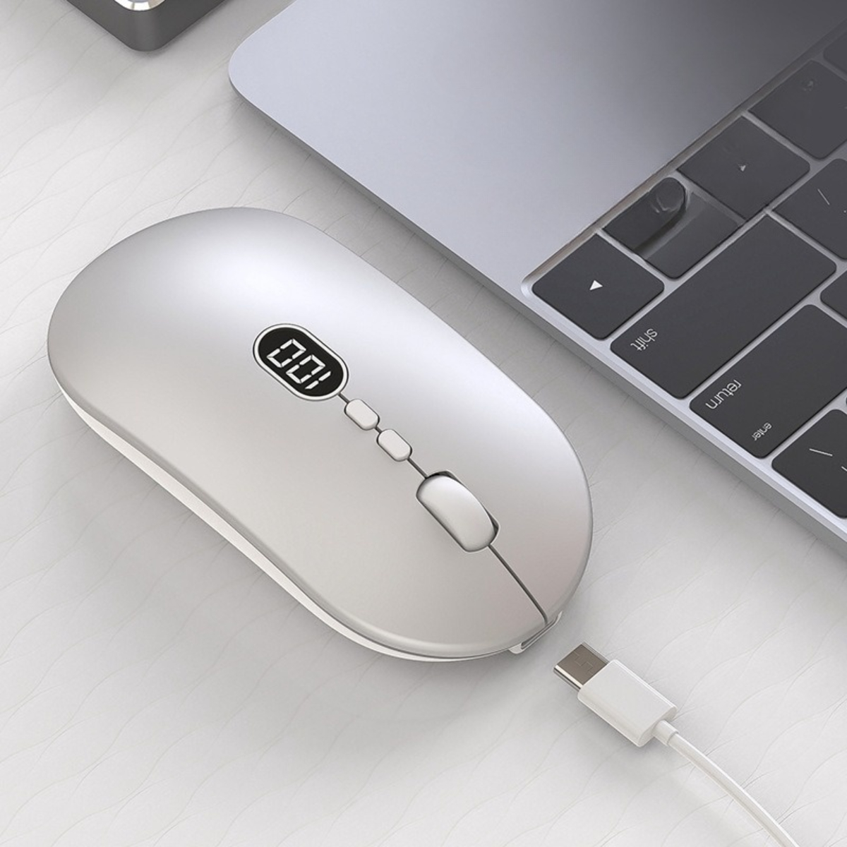 Eine silberne Computermaus mit kleinem Bildschirm, über ein USB-Kabel mit einem Laptop verbunden.