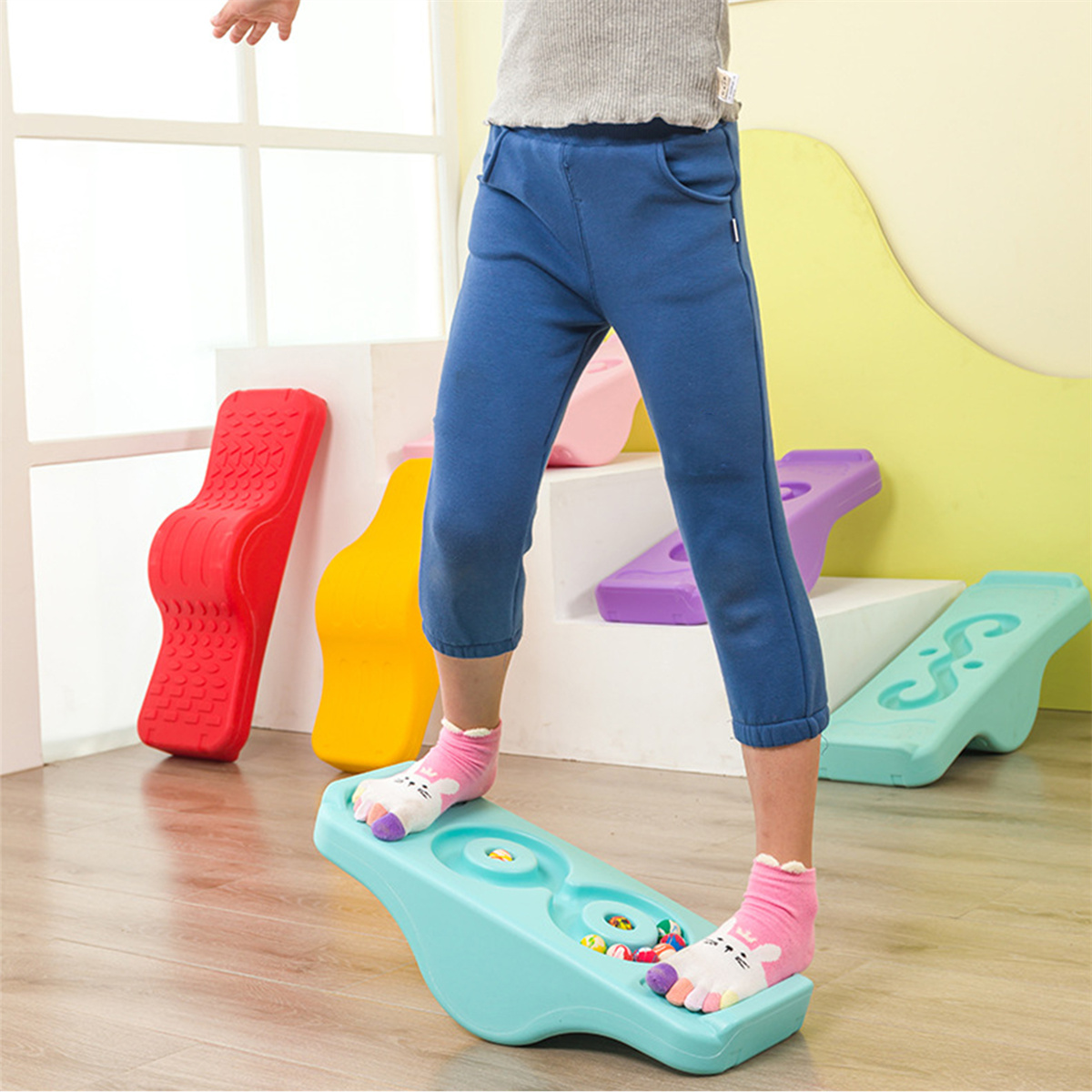 Ein Kind steht auf einem Balance Board, mit anderen Balance Boards herum.