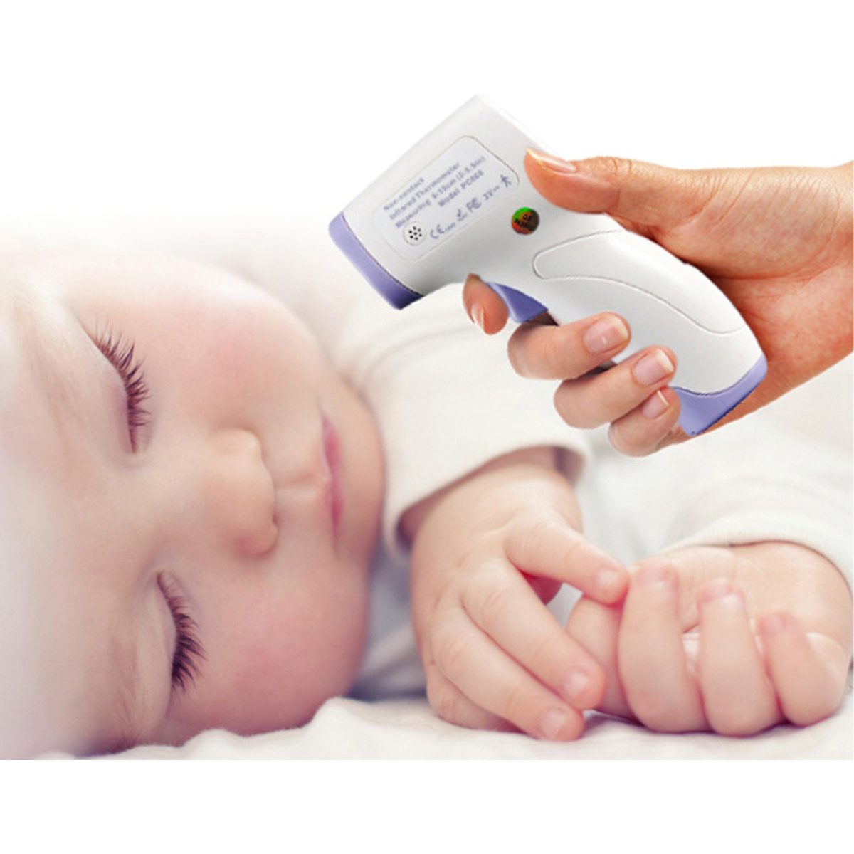 Schlafendes Baby, Hand am Gesicht, Thermometer auf der Stirn, weißer Hintergrund.