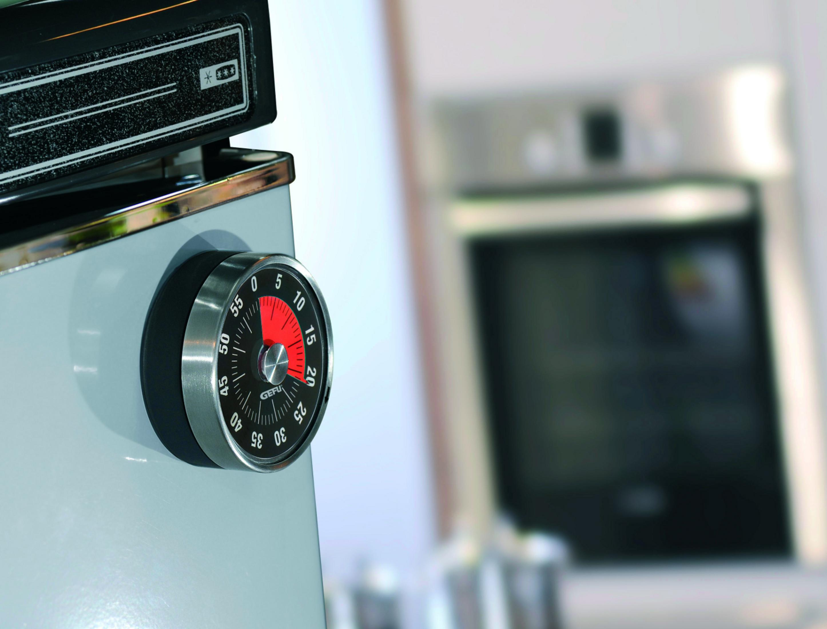 Timer da cucina nero e argento su una superficie grigia, che mostra 15 minuti. Cucina sullo sfondo.