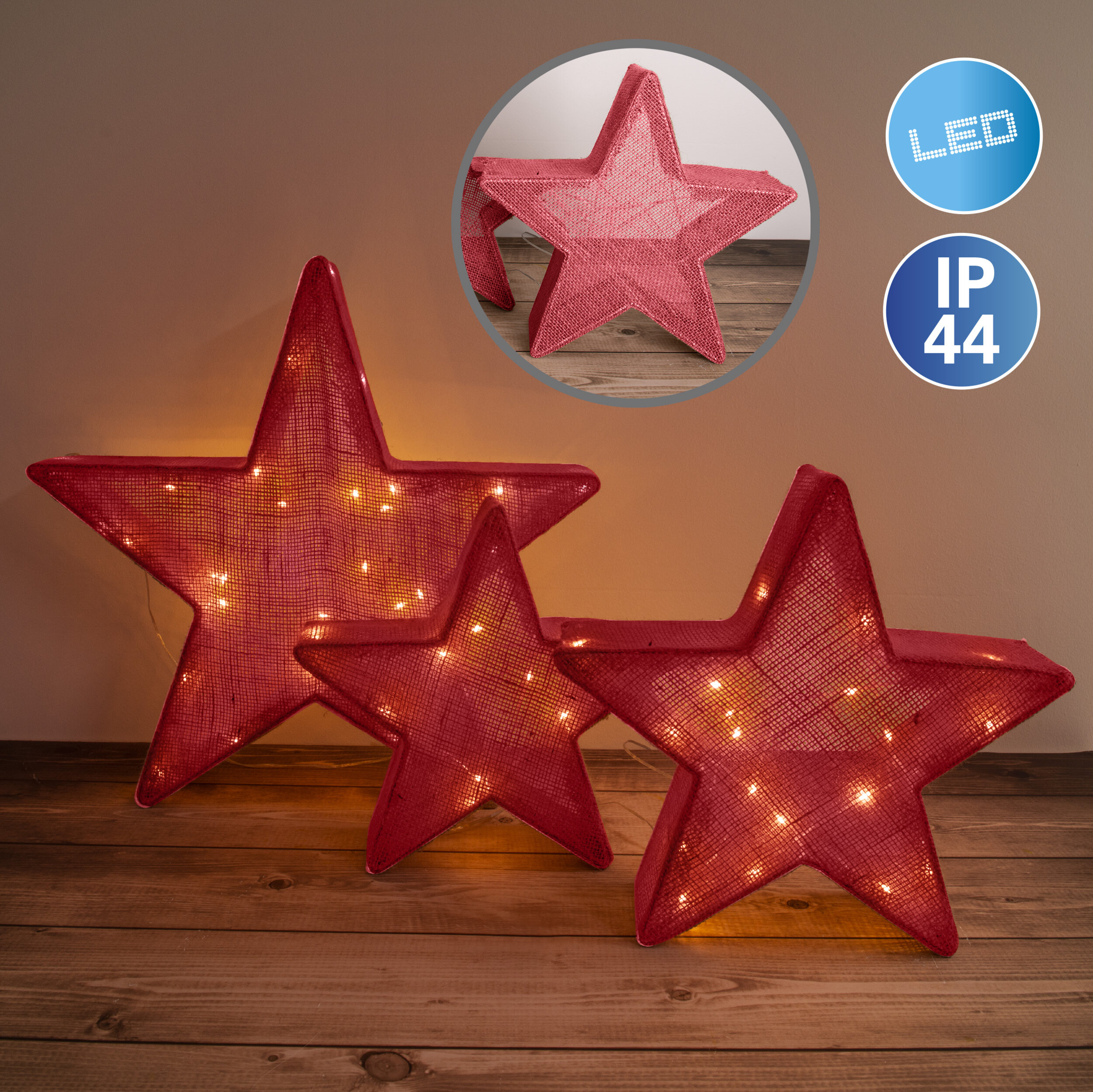 Drei rote sternförmige Lichter auf einer Holzoberfläche mit einem kleineren Stern als Einsatz.